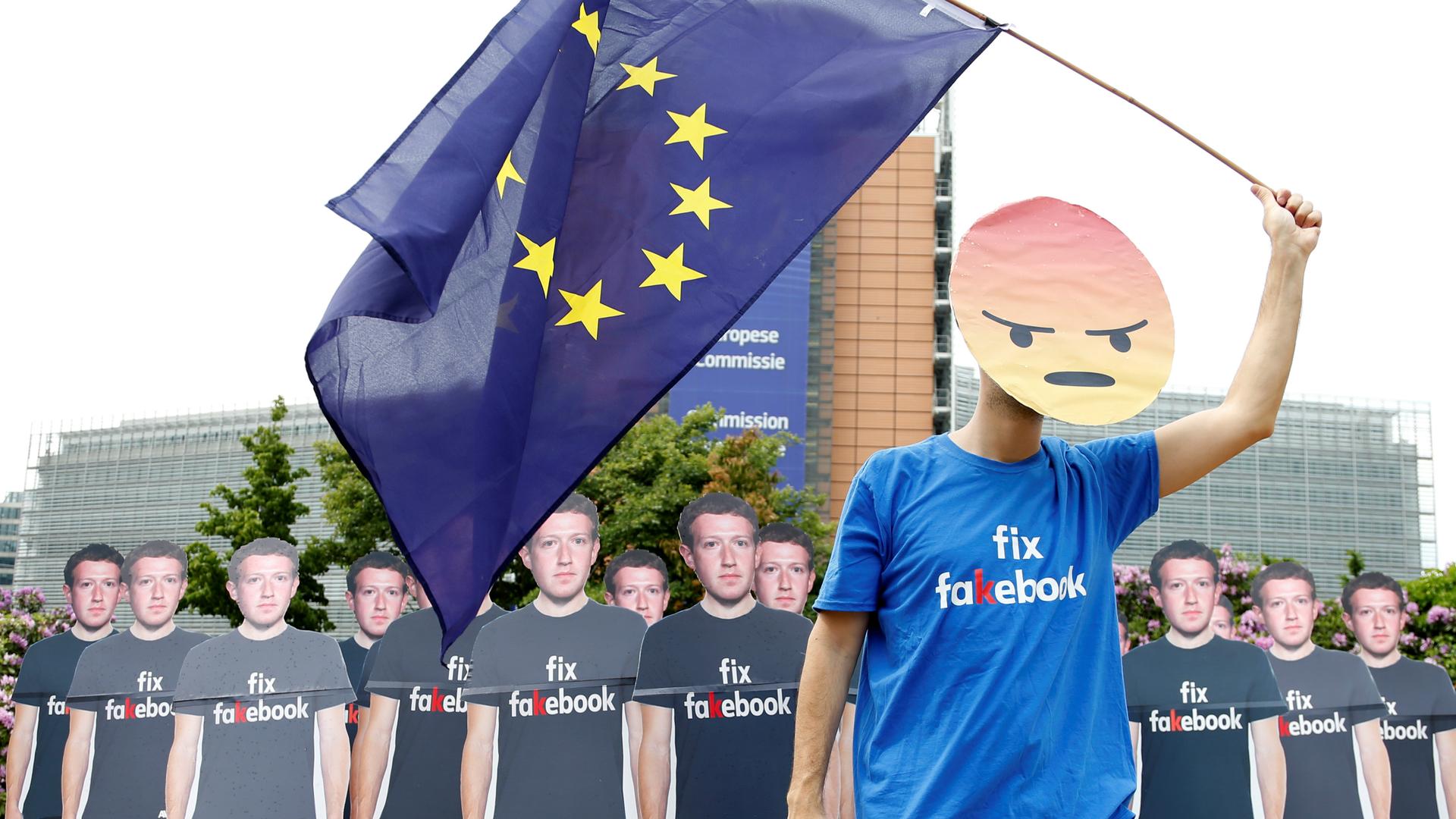 A protester holds an European Union flag next to cardboard cutouts depicting Facebook CEO Mark Zuckerberg during a demonstration ahead of a meeting between Zuckerberg and leaders of the European Parliament in Brussels, Belgium, May 22, 2018.