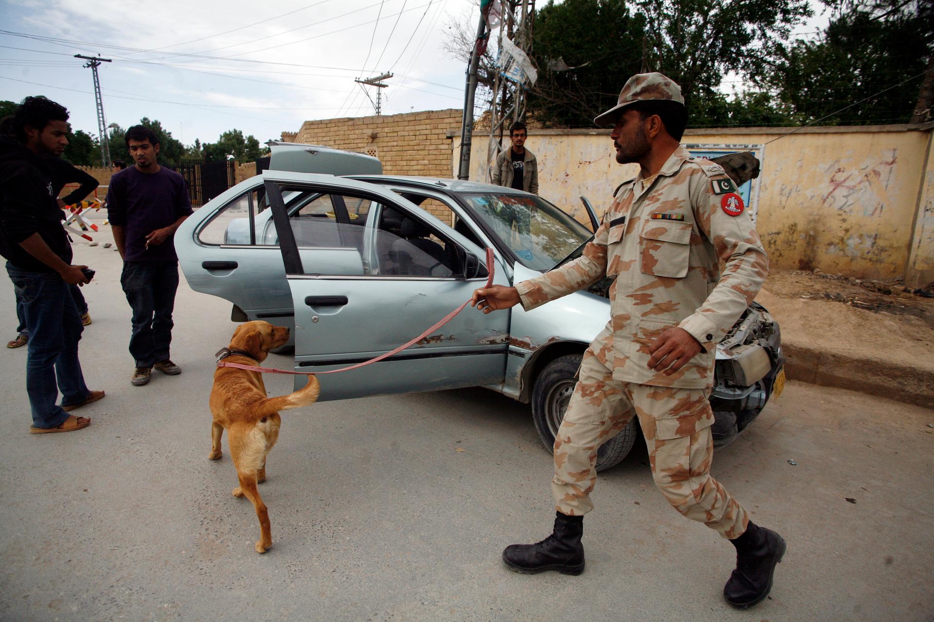 A Pakistani soldier and his sniffer dog search a vehicle at the entrance of a Hazara neighborhood in Quetta, Pakistan,