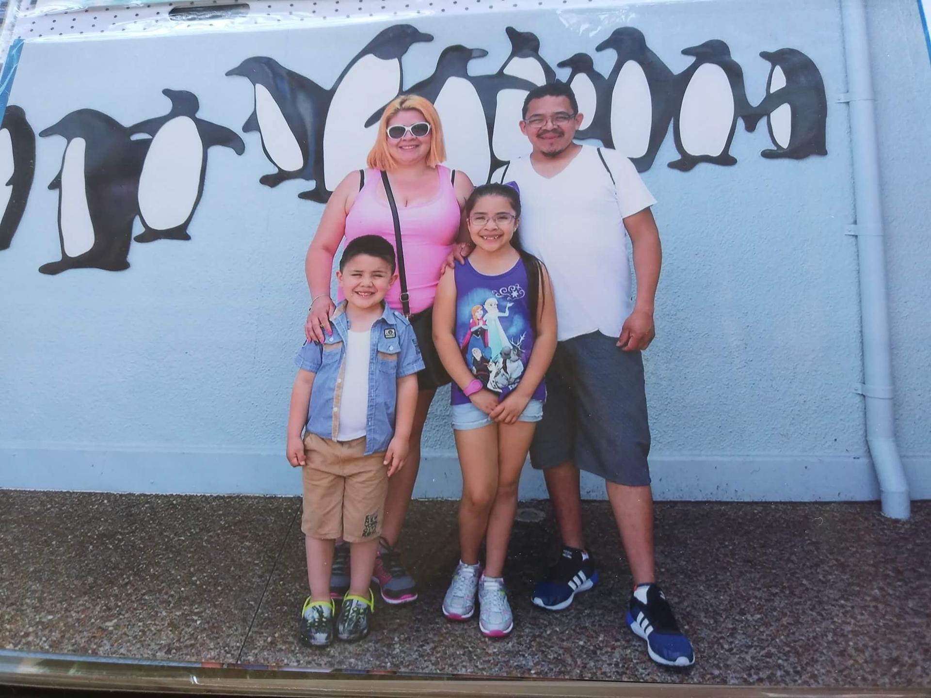 Photo of a photo of family in front of wall with penguins painted on it