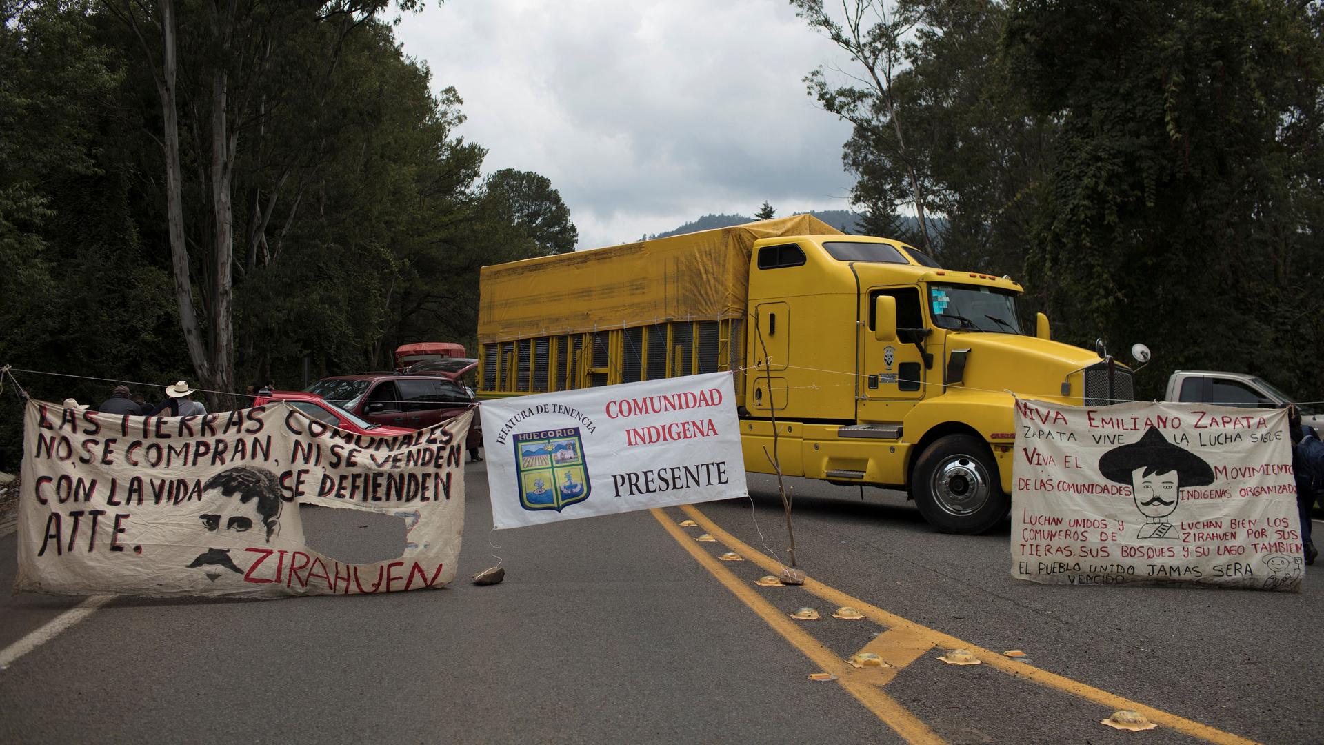 Cloth banners and a yellow truck block a road.