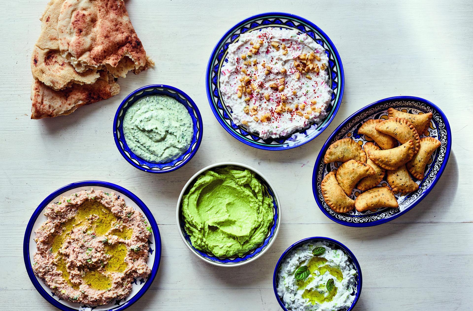 Dips and Small Bites from The Palestinian Table: (clockwise from left) Taboon Bread; Parsley or Cilantro (Coriander) Tahini Spread; Walnut and Garlic Labaneh; Deep-Fried Cheese and Za’atar Parcels; Garlic and Cucumber Labaneh; Avocado, Labaneh, and Preser