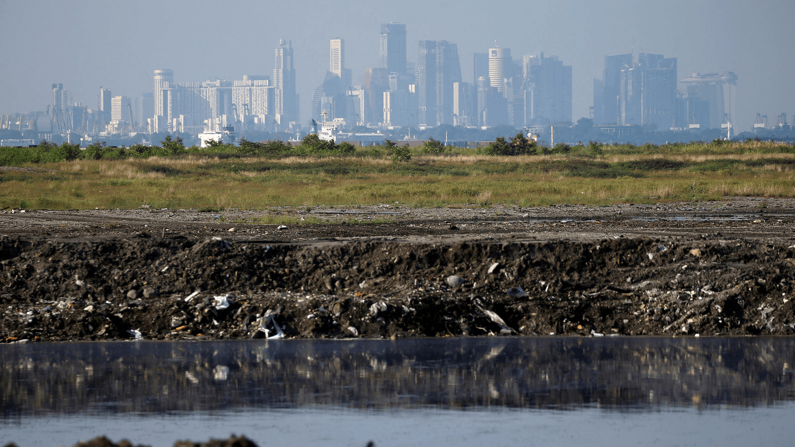 the singapore skyline in the background and a landfill in the foreground