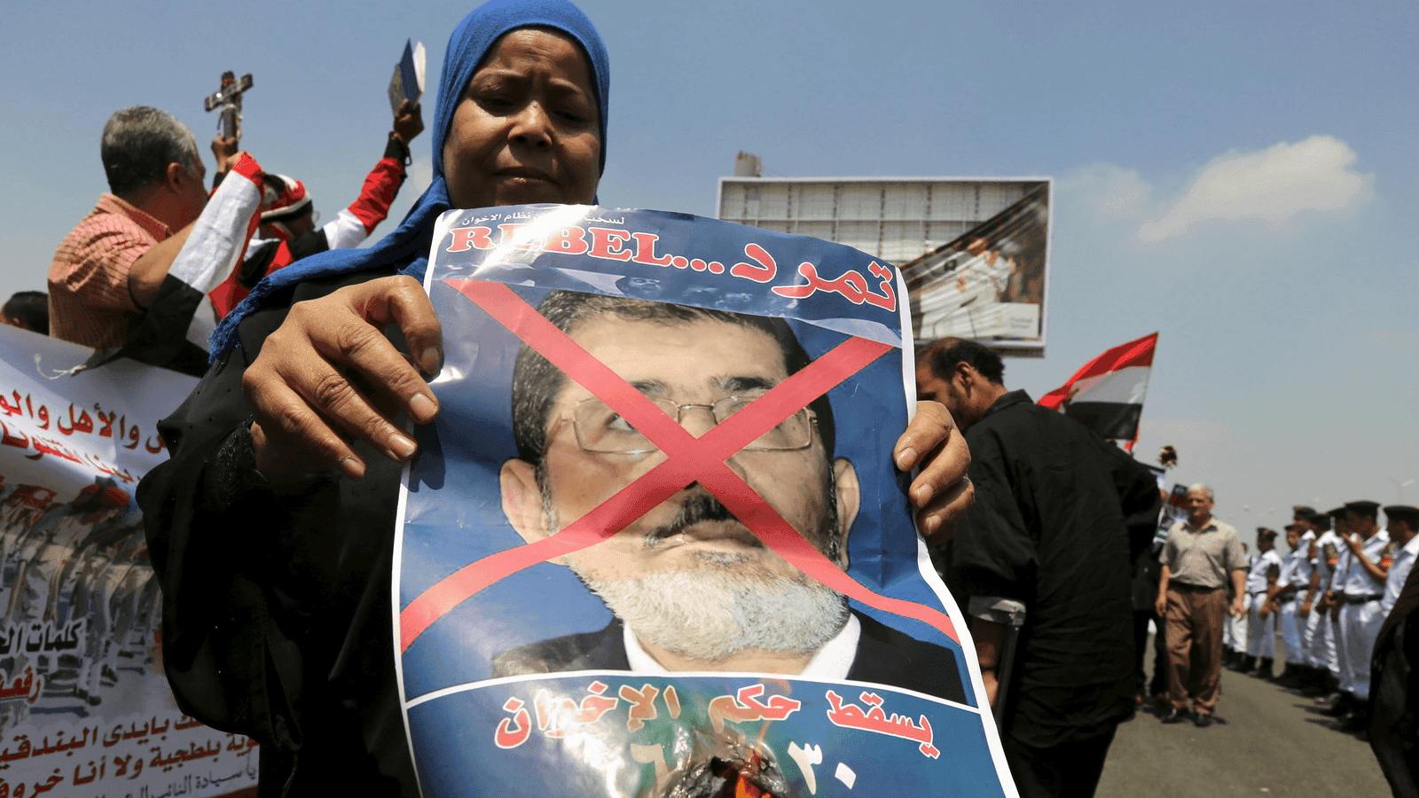A woman burns a portrait of ousted President Mohamed Mursi at the funeral of Egyptian public prosecutor Hisham Barakat, on the second anniversary of the June 30 protests, in Cairo, Egypt, June 30, 2015. 