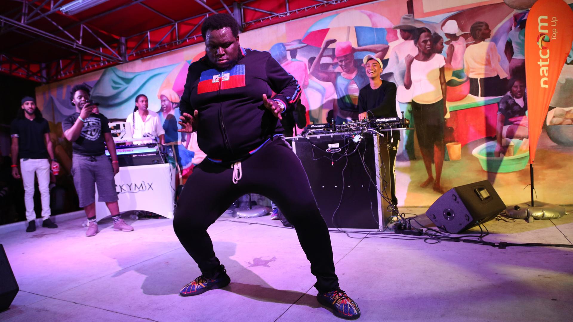 A fan dressed in a sweatshirt with the Haitian flag on it, joins DJ Michael Brun on stage at the Bayo Block Party in Miami, Flordia.
