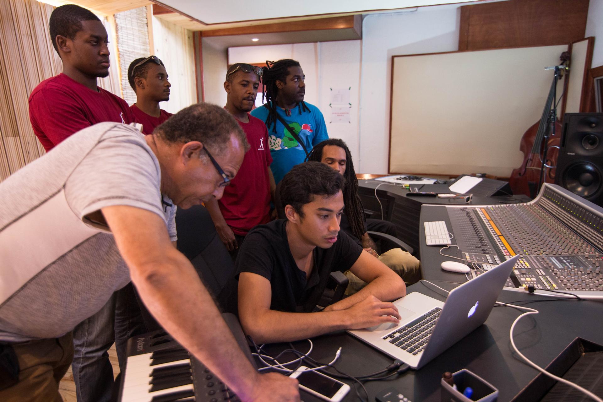Michael Brun sits at a digital audio workstation with students at the Audio Institute in Jacmel, Haiti.