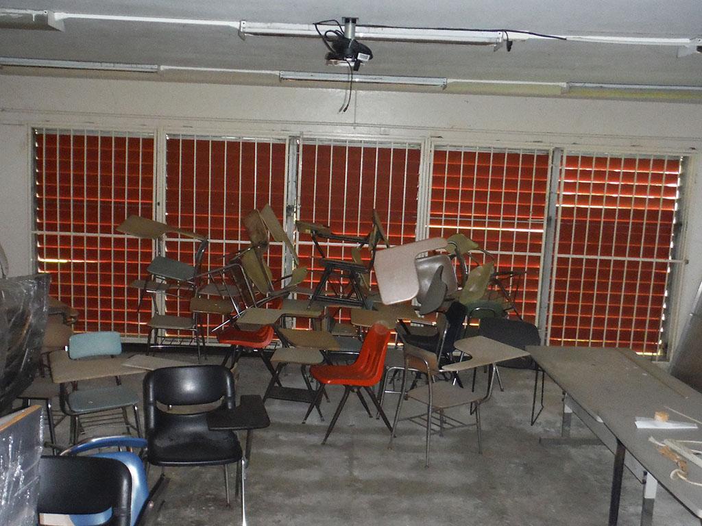 A bunch of chairs piled up in a classroom.