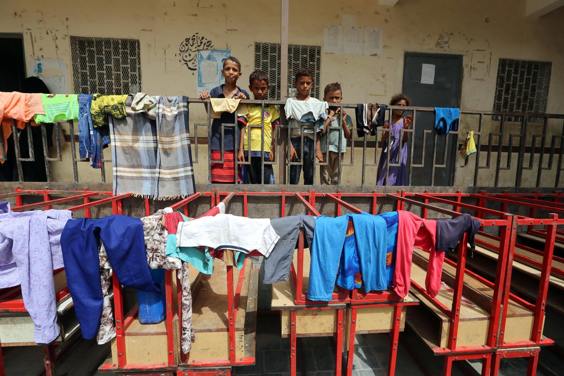Children stand behind a fence at a school to which they have been evacuated from a village near Hodeidah airport amid fighting between government forces and Houthi fighters in Hodeidah,