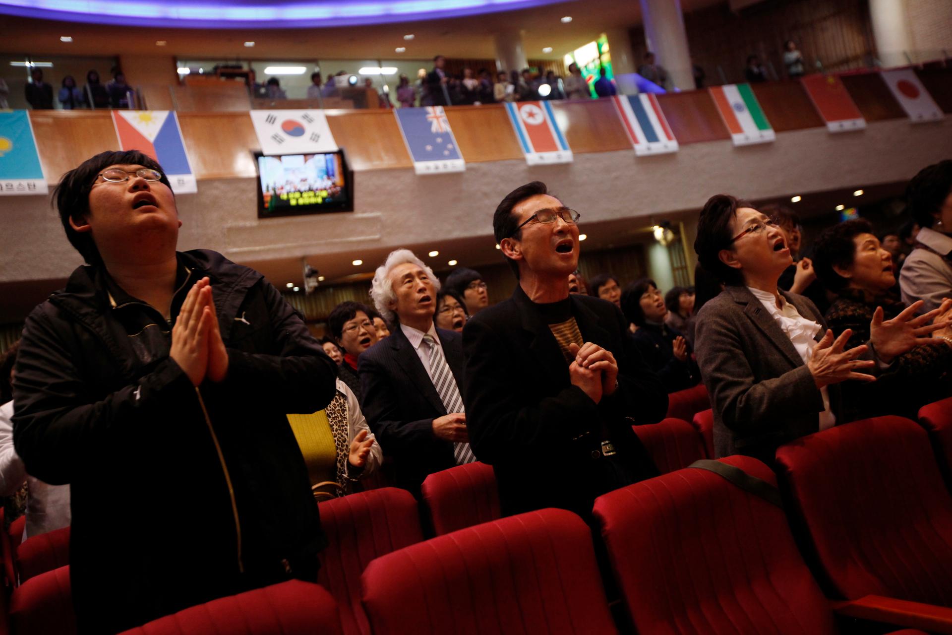 South Korean Christians pray for peace on Korean peninsula in a church where the North Korean national flag hangs among other countries' national flags in Icheon, South Korea, March 31, 2013. Holy Week is celebrated in many Christian traditions during the