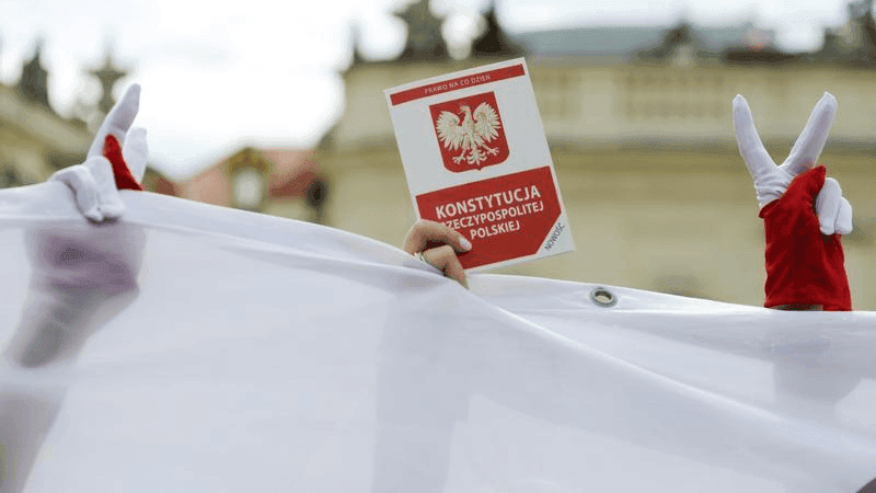 A demonstrator holds a copy of the Polish Constitution