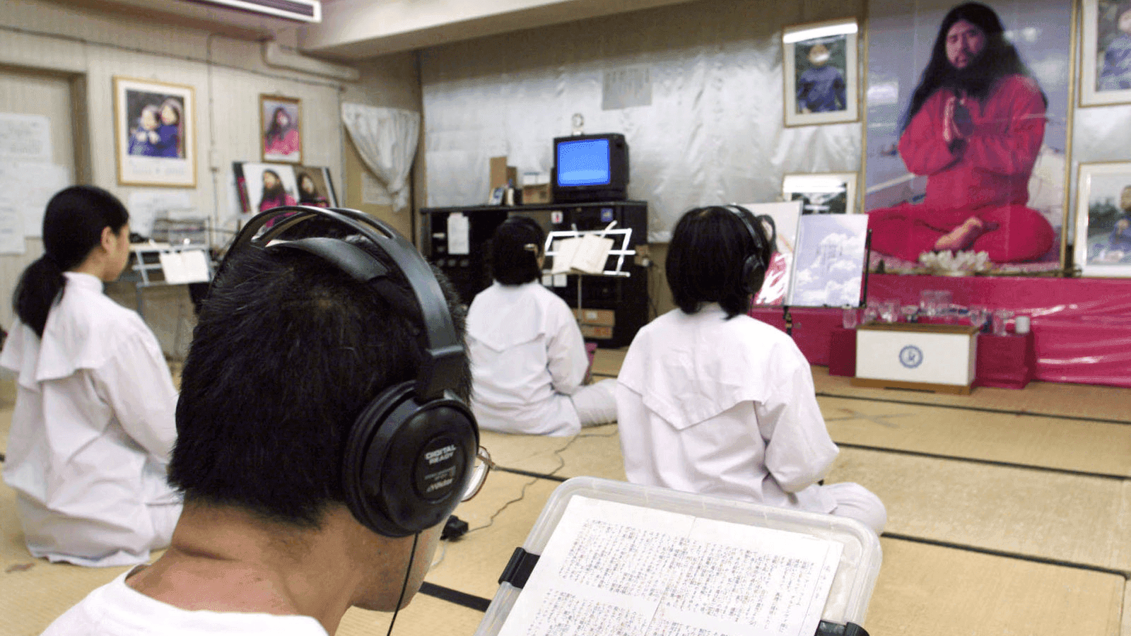 followers of a cult in japan chant before a portrait of their leader