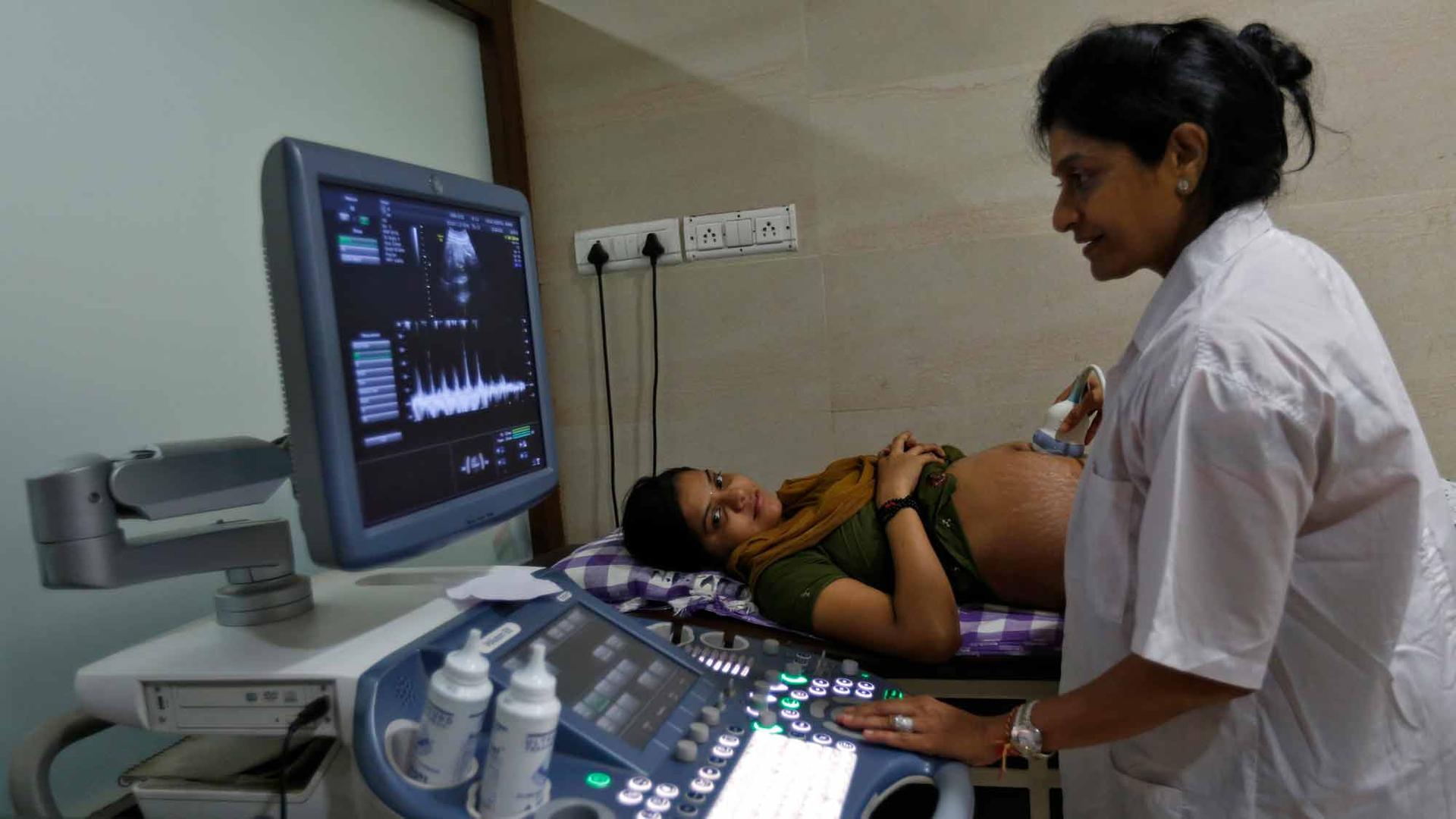 A female doctor performs an ultrasound on a pregnant patient.