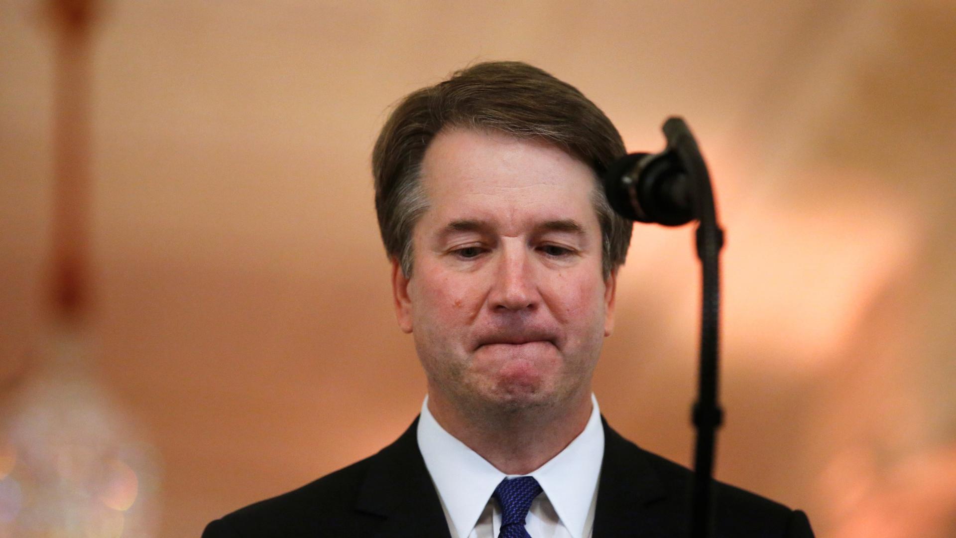 US Supreme Court nominee judge Brett Kavanaugh is shown looking down at a microphone.