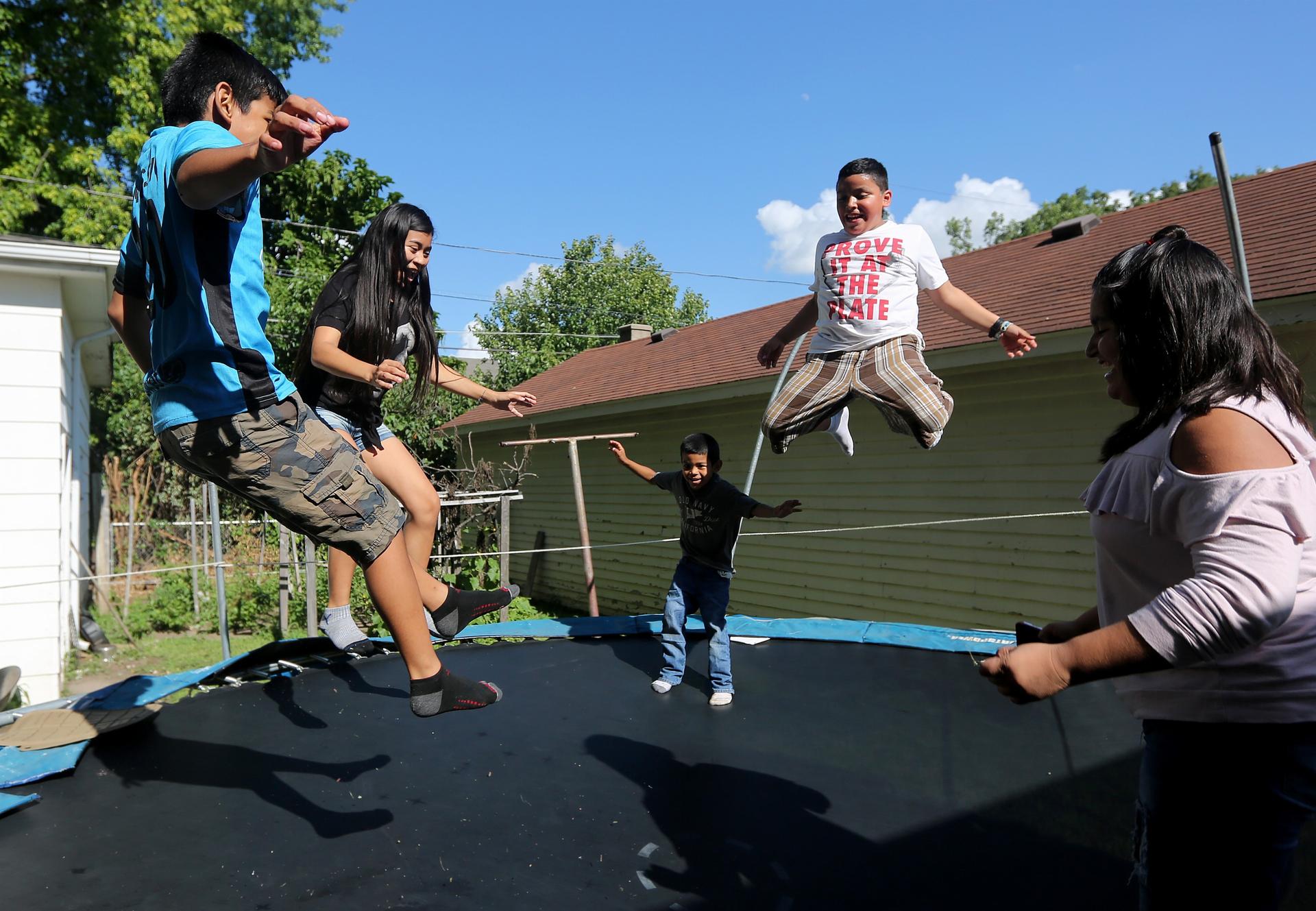 Children jump on trampoline outdoors