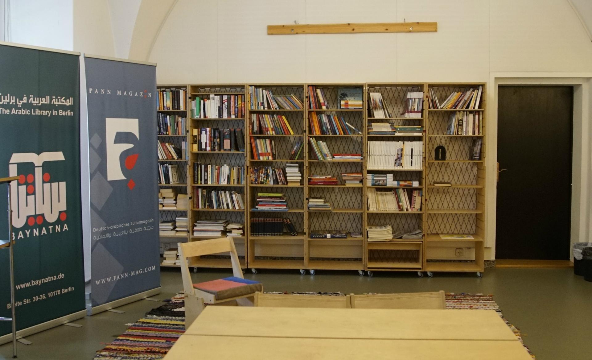 The library is built out of custom bookshelves and tables that are designed to be moved and stored easily, in case of a change in location. It's decorated with rugs woven from old clothing.