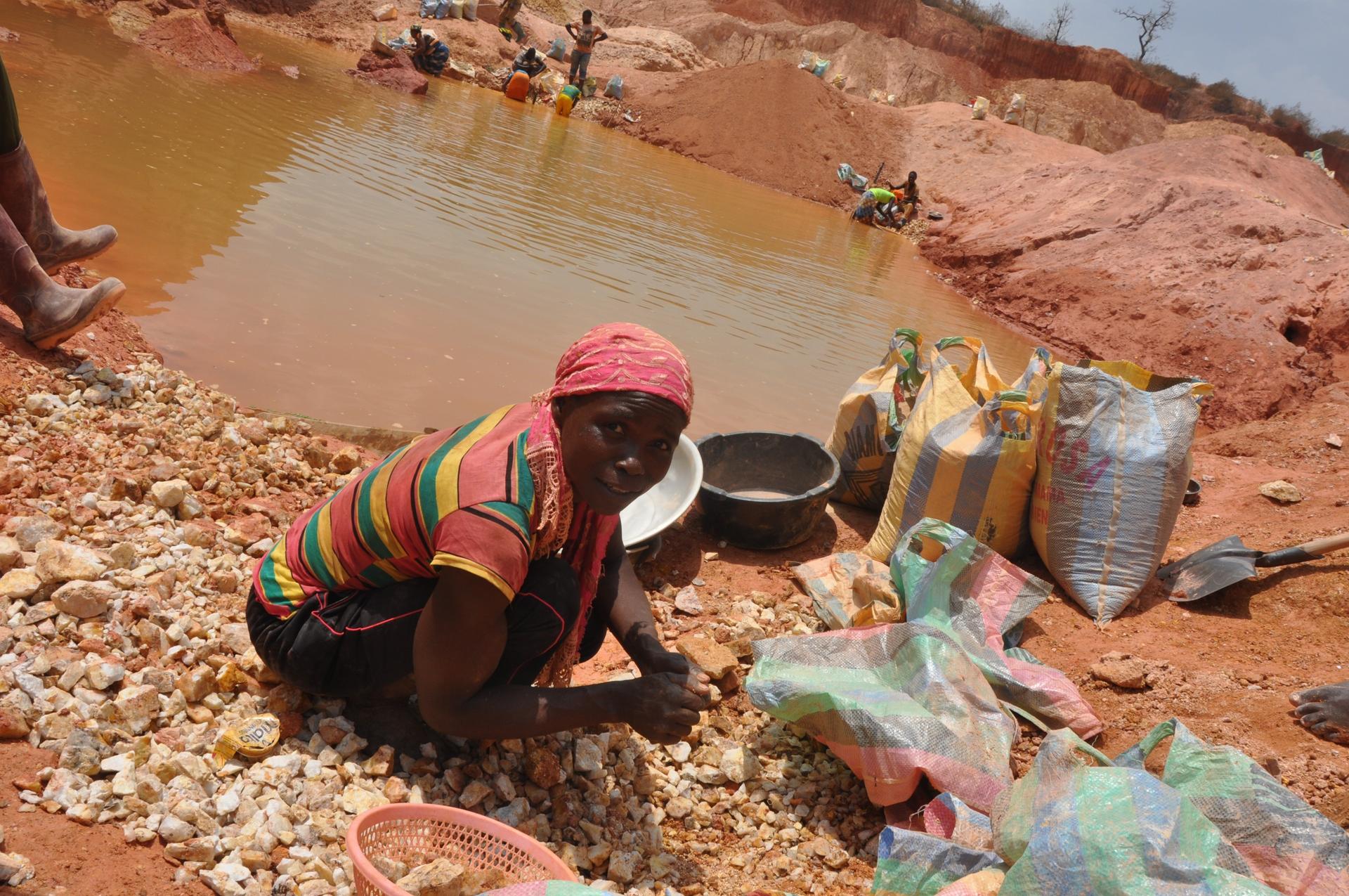 Sidonie Maboue, 45, a widow and mother, picks up small rocks from a mine site abandoned by Chinese miners. These pebbles are later crushed and sieved to collect gold.