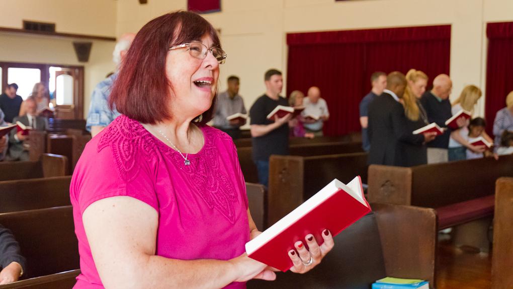 Woman in church holding book and singing
