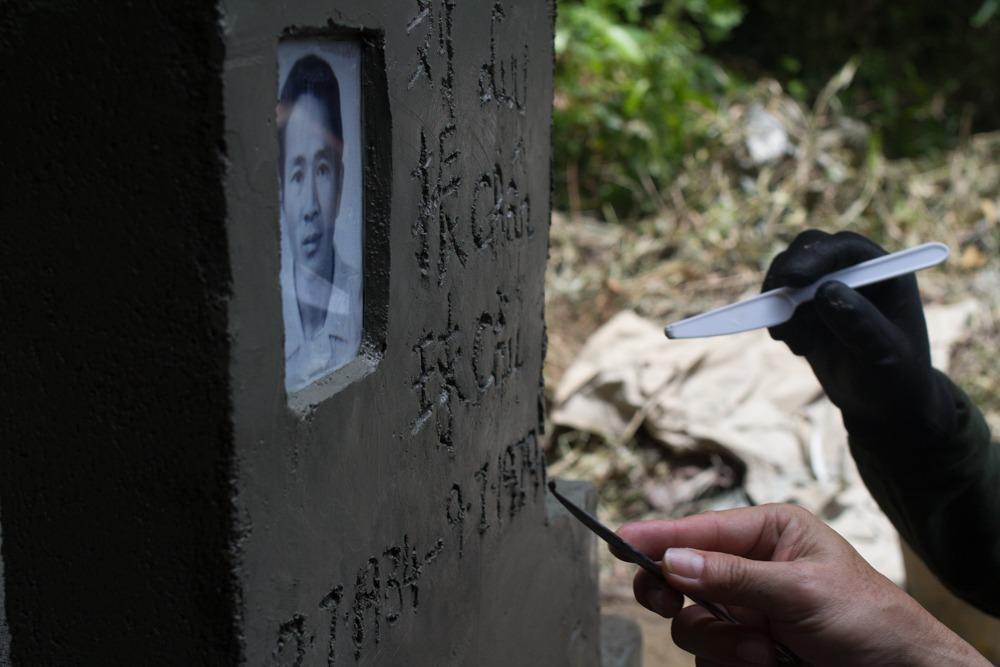 Tony and Daniel Luu etch their father’s tombstone on the Indonesian island of Kuku.