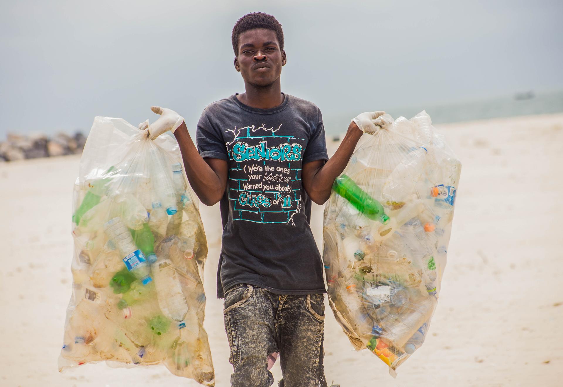 A volunteer in Nigeria collects waste on a beach during the Ocean Conservancy’s annual International Coastal Cleanup. Plastic straws were the seventh most common type of trash found last year.