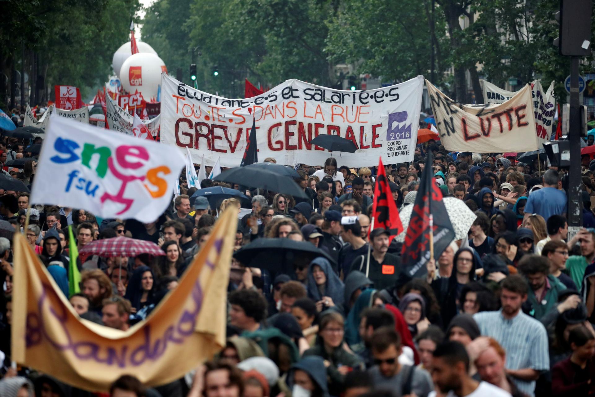 French civil servants and students carry labor union flags and banners as they march in protest during a national day of strikes by public sector workers, in Paris, France, May 22