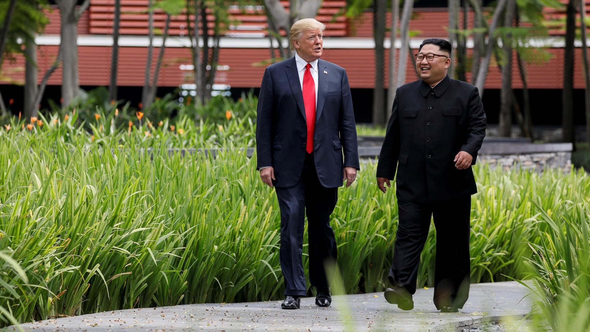 President Donald Trump and North Korea's leader Kim Jong-un walk together before their working lunch during their summit at the Capella Hotel on the resort island of Sentosa, Singapore on June 12, 2018. 