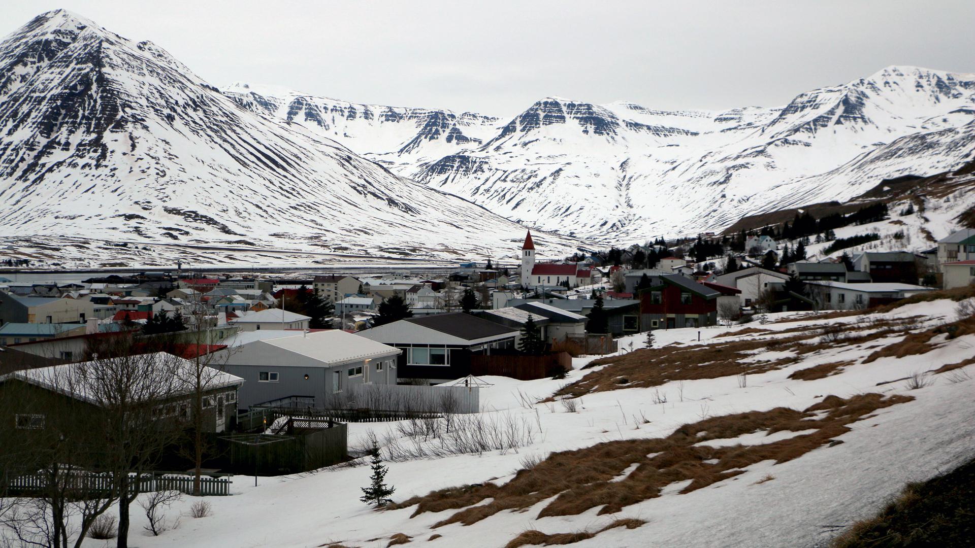 A town is blanketed in snow and flanked by a mountain