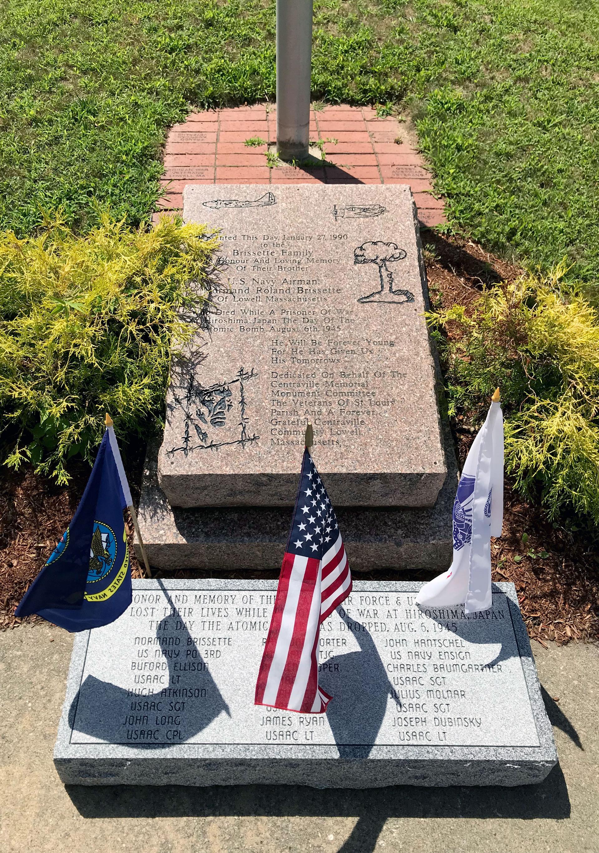 Flags hang next to a stone memorial engraved with names