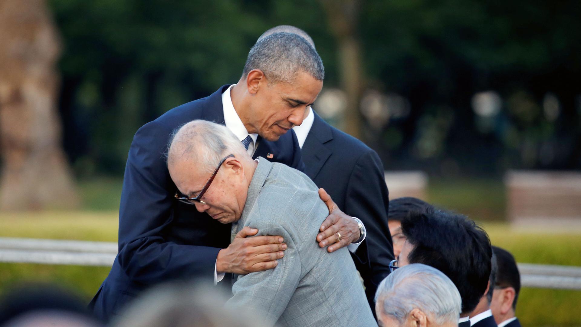 An older Japanese man hugs former President Barack Obama