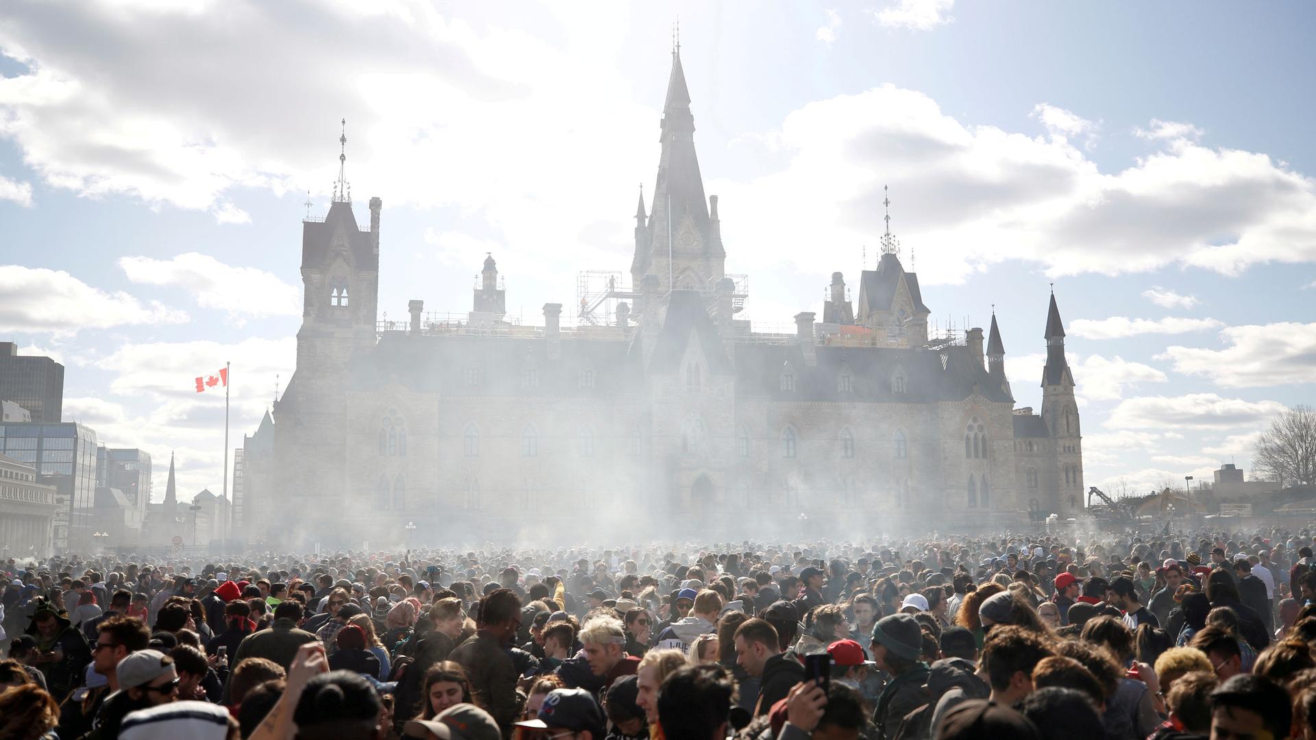 Smoke rises above a crowd assembled in front of the Ottawa government building