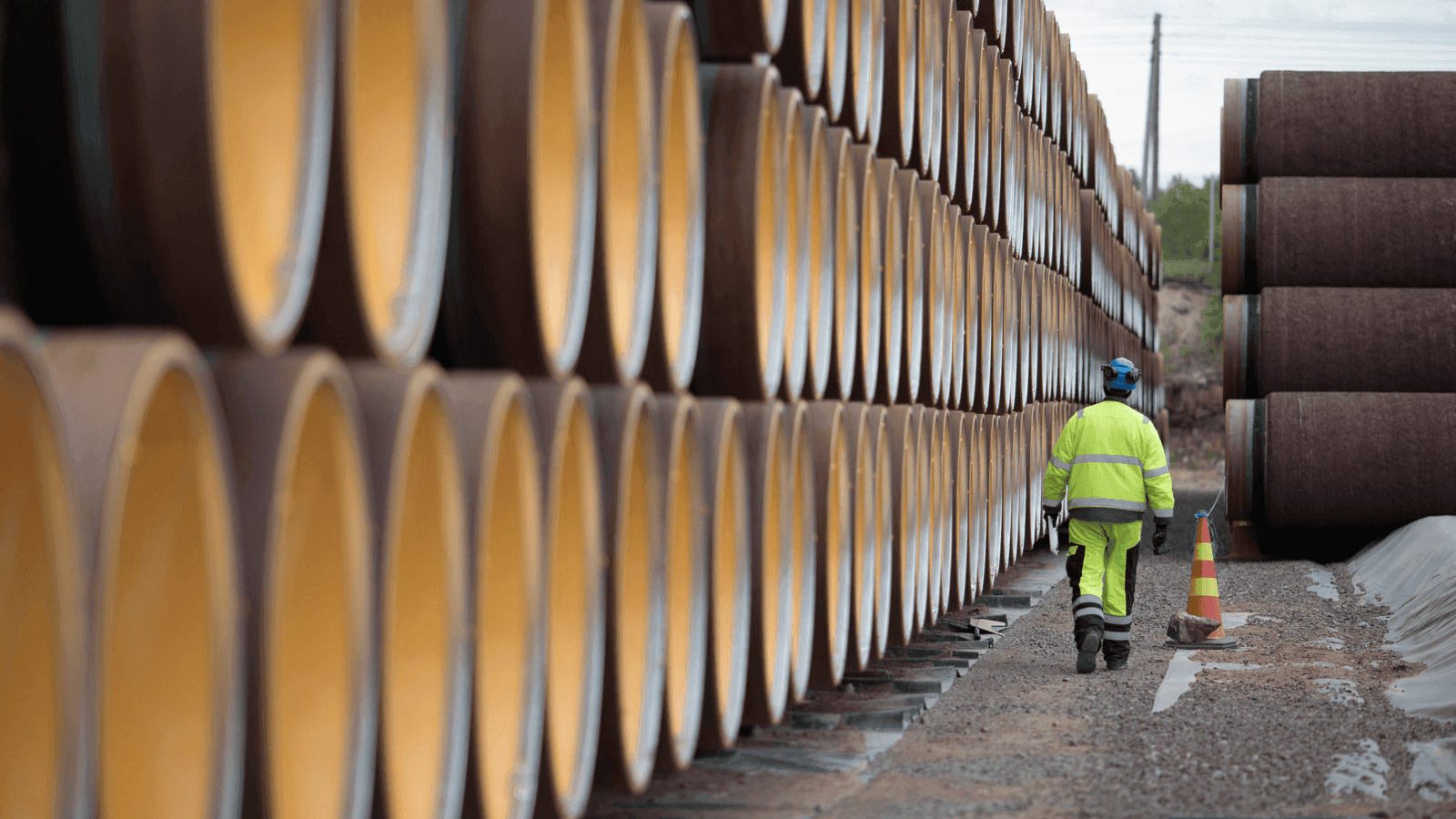 a worker walks alongside an oil pipeline 