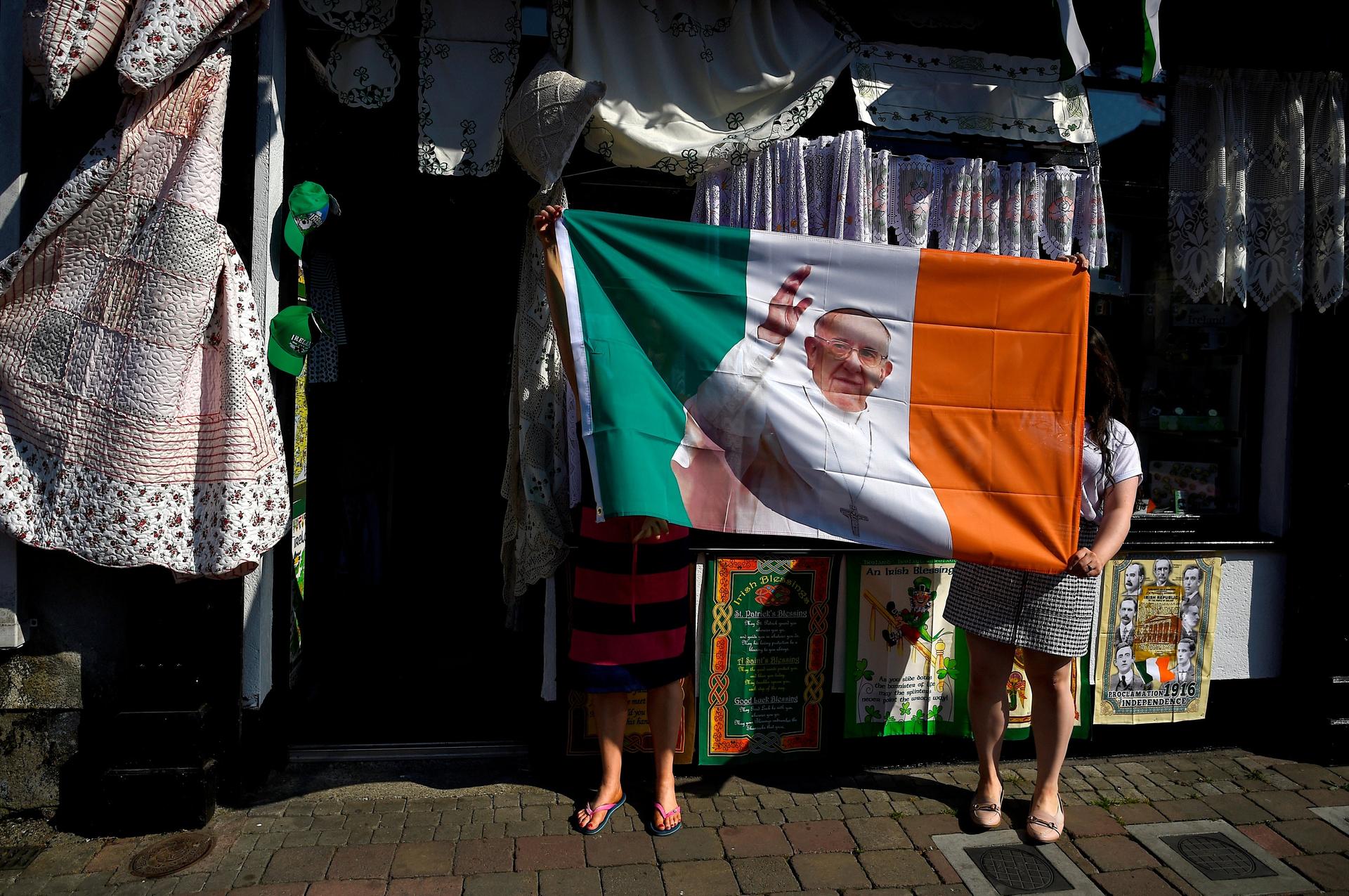 Women from a haberdashery shop hold up their new Pope Francis Ireland flag