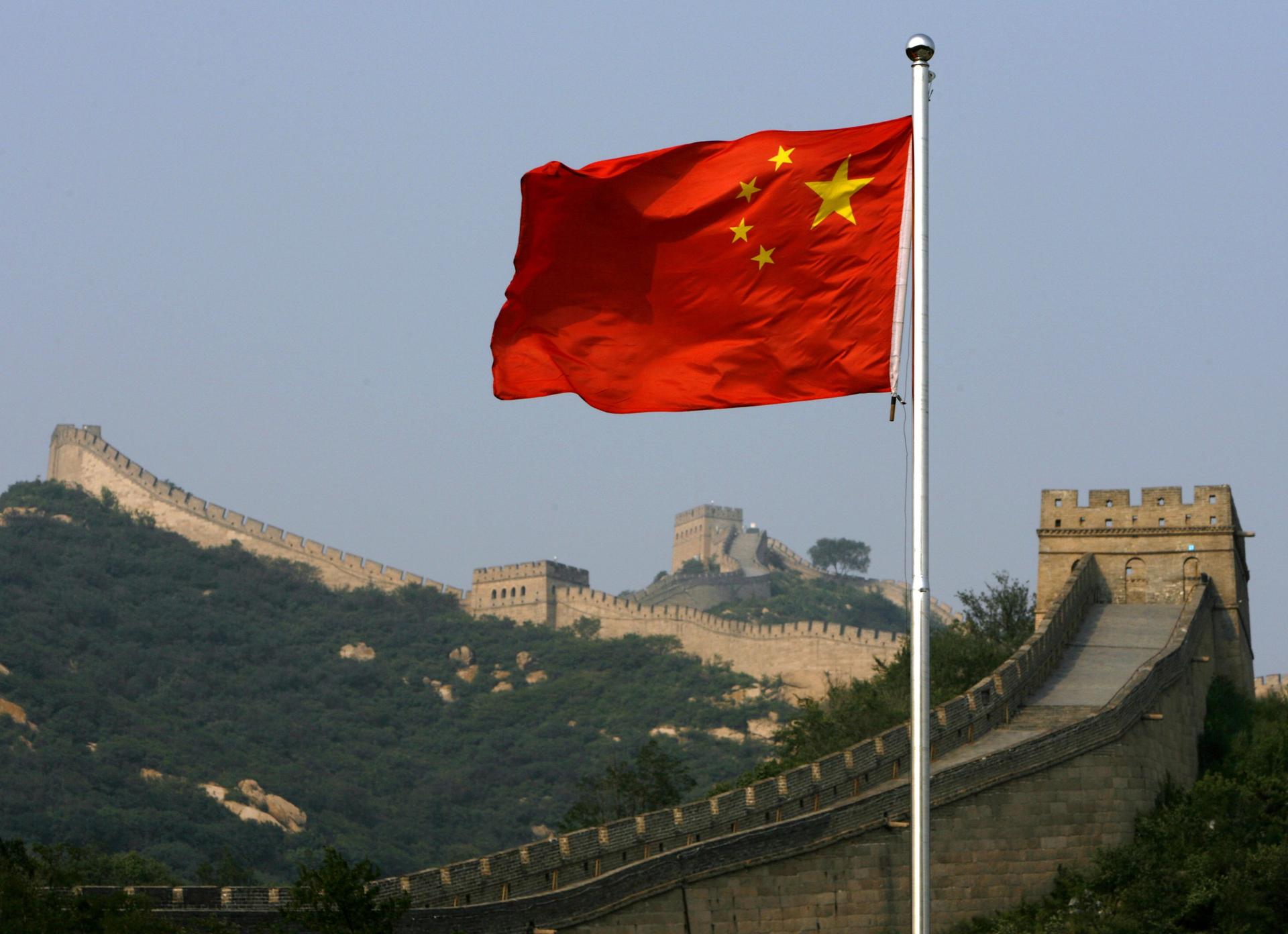 A Chinese flag flies in front of the Great Wall of China