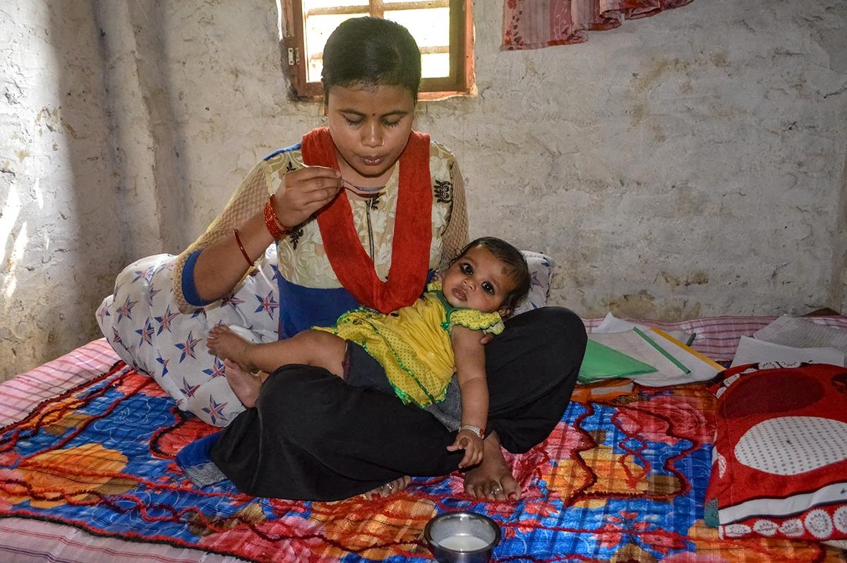 a nepali woman feeds her small daughter