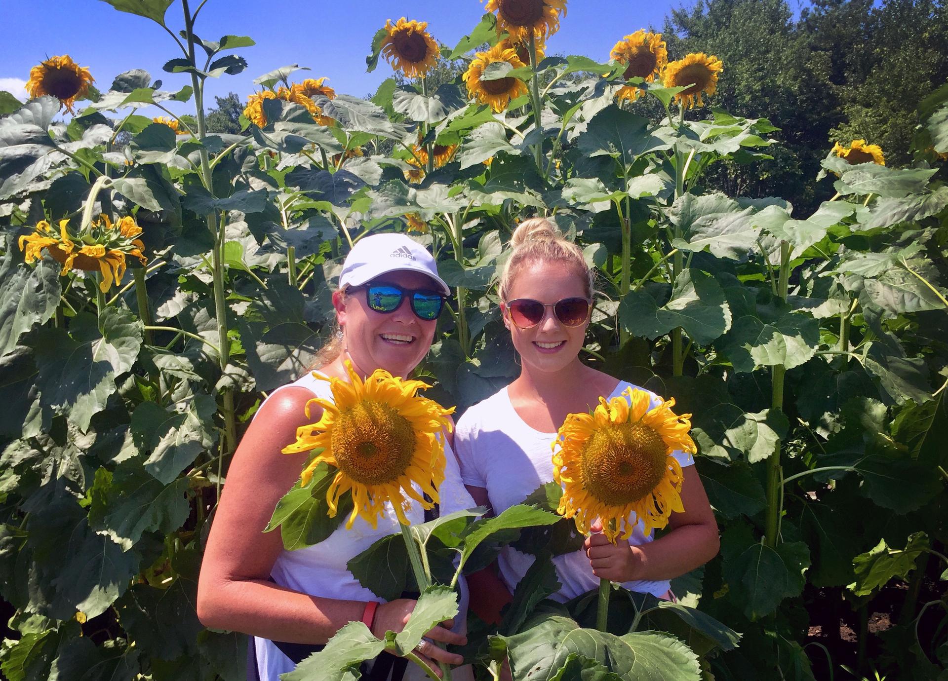 Two women in a sunflower field.