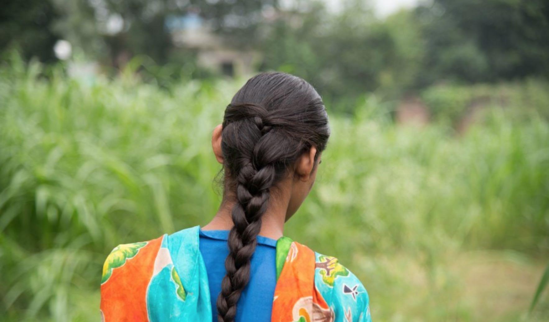 Razia, who has an intellectual disability and difficulties with speech, is depicted with her back to the camera looks out and wearing traditional patterns from India.