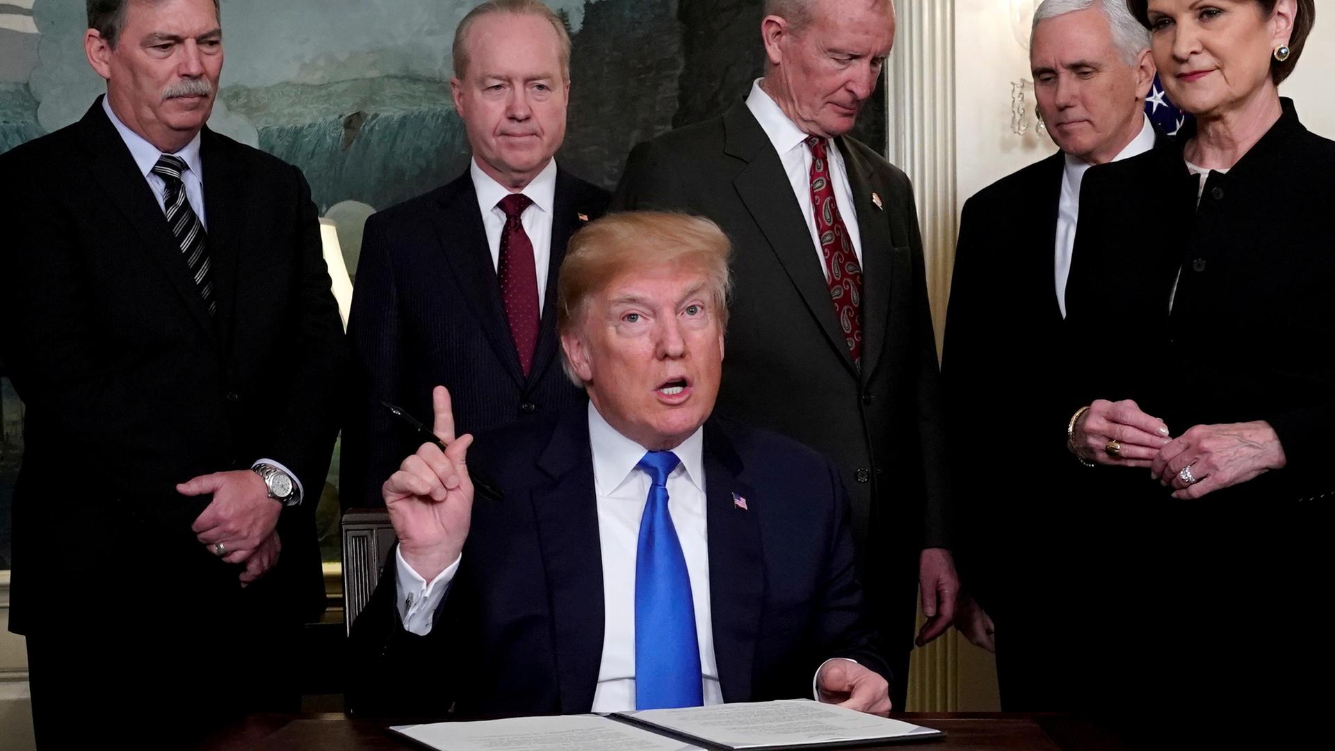 President Donald Trump, surrounded by business leaders and administration officials, prepares to sign a memorandum on intellectual property tariffs on high-tech goods from China, at the White House in Washington, March 22, 2018. 