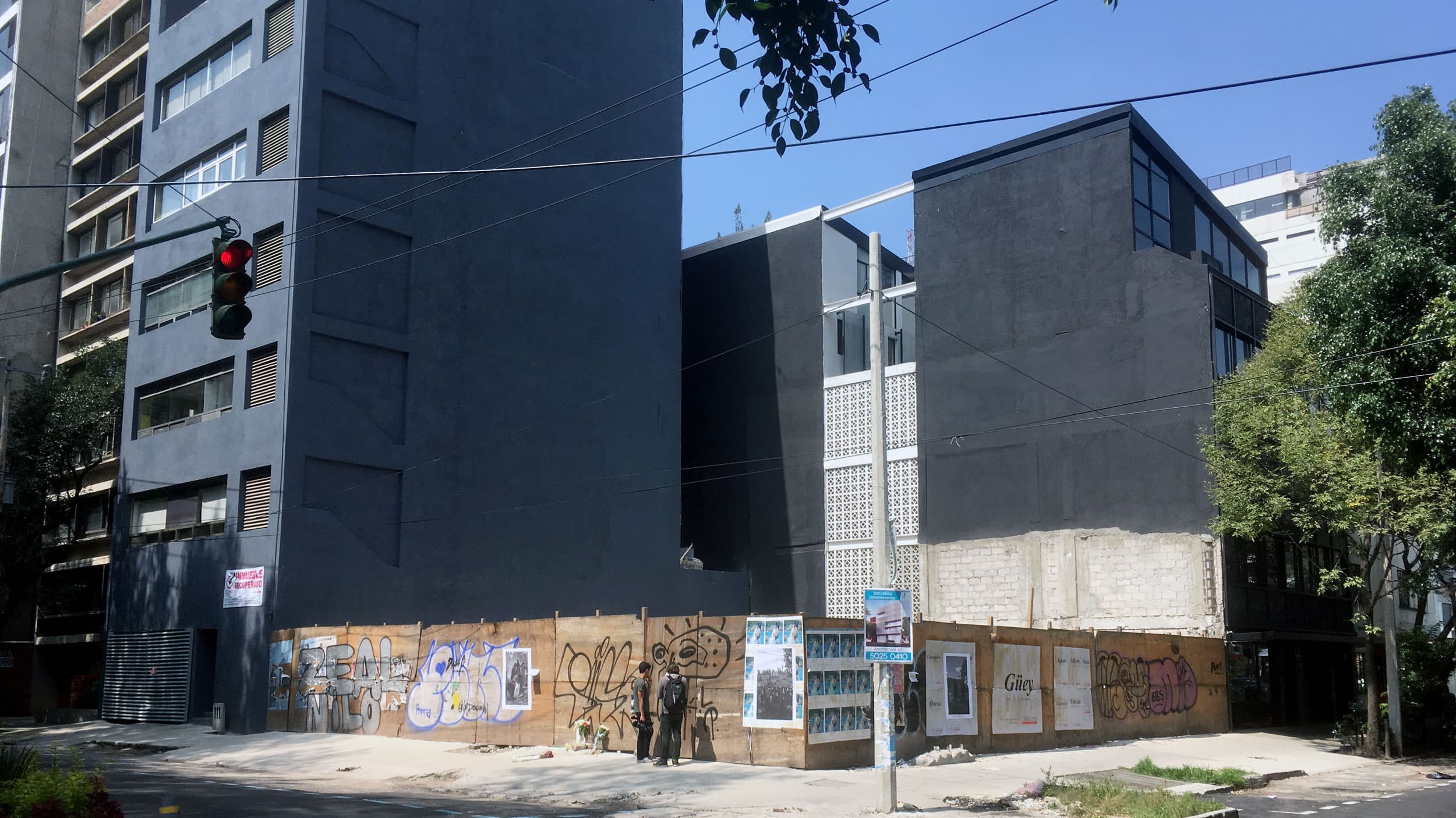 People stand next to a temporary wall marking where a building used to be