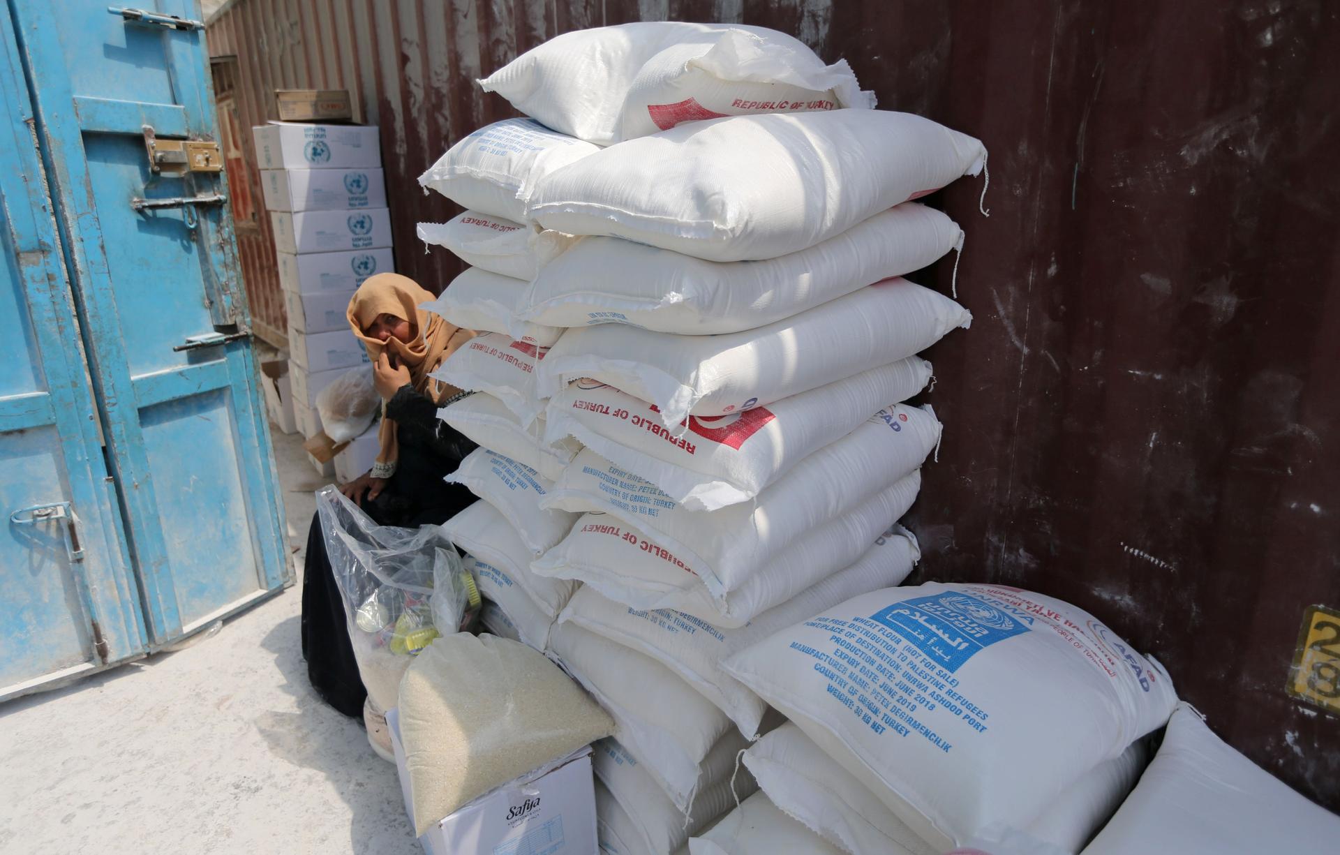 A Palestinian woman sits next to bags of flour