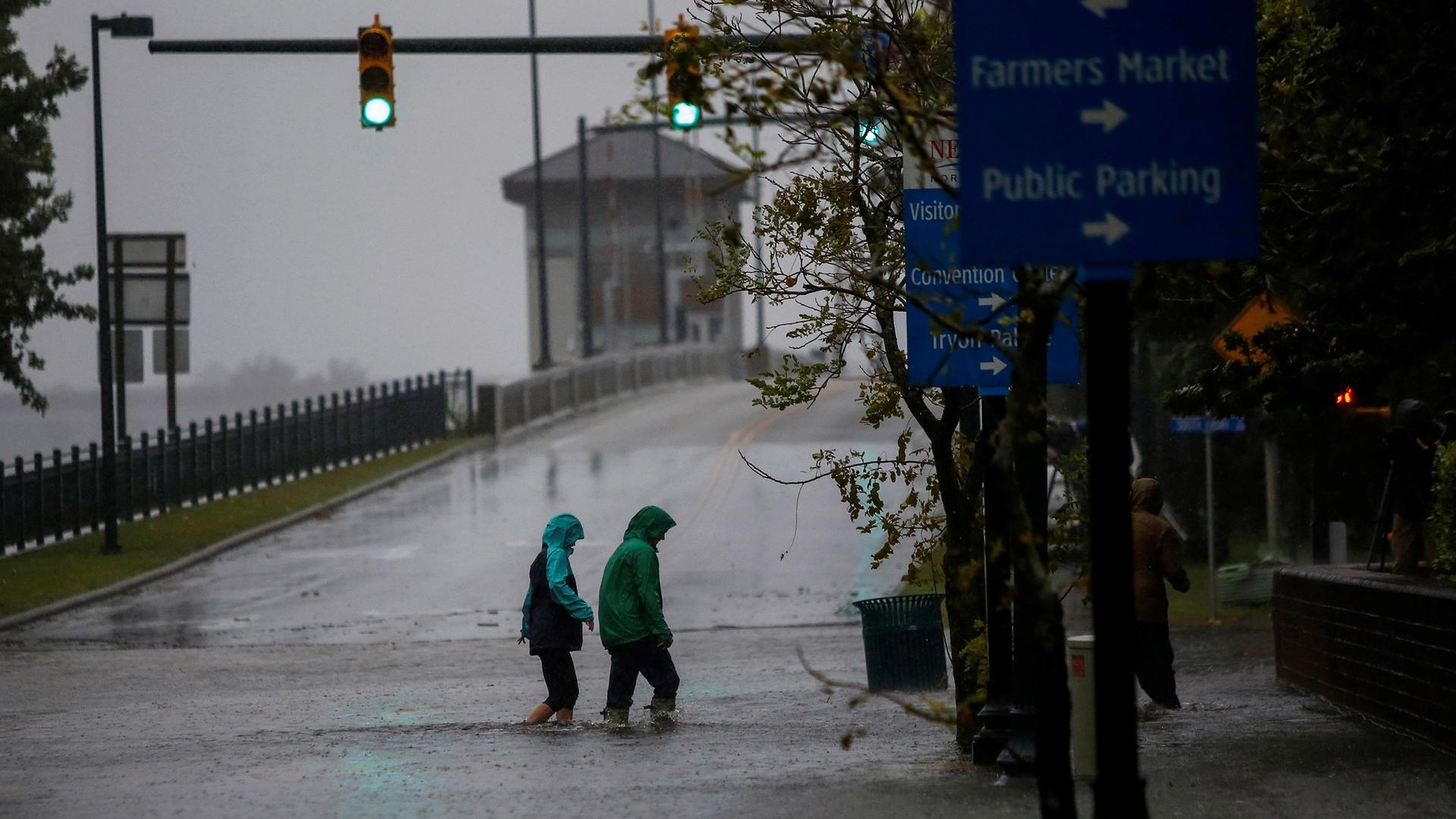 People are shown in rain jackets wading through a flooded street in New Bern, North Carolina, Sept. 13, 2018.