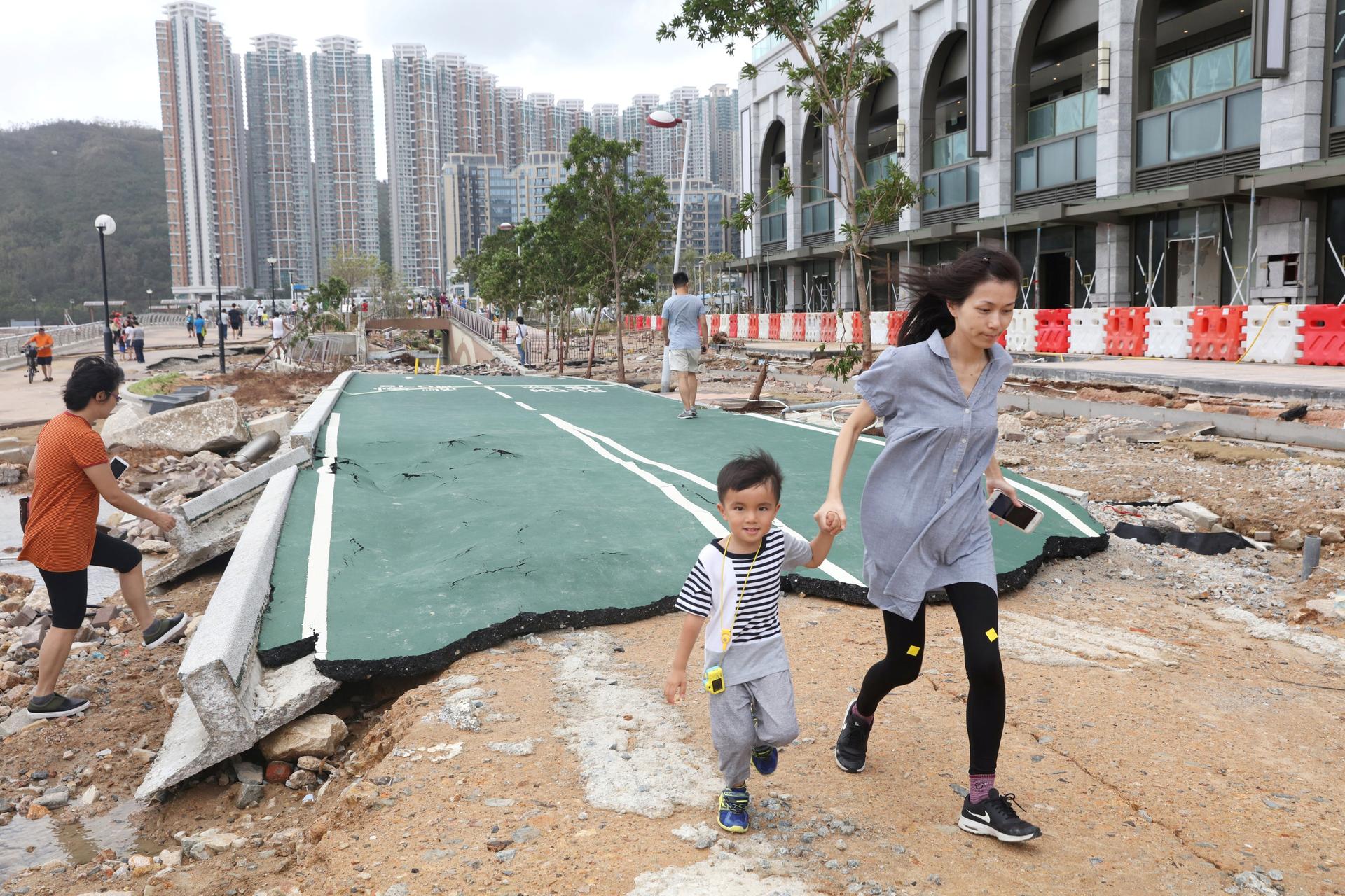 A boy and his mother walk through rubble