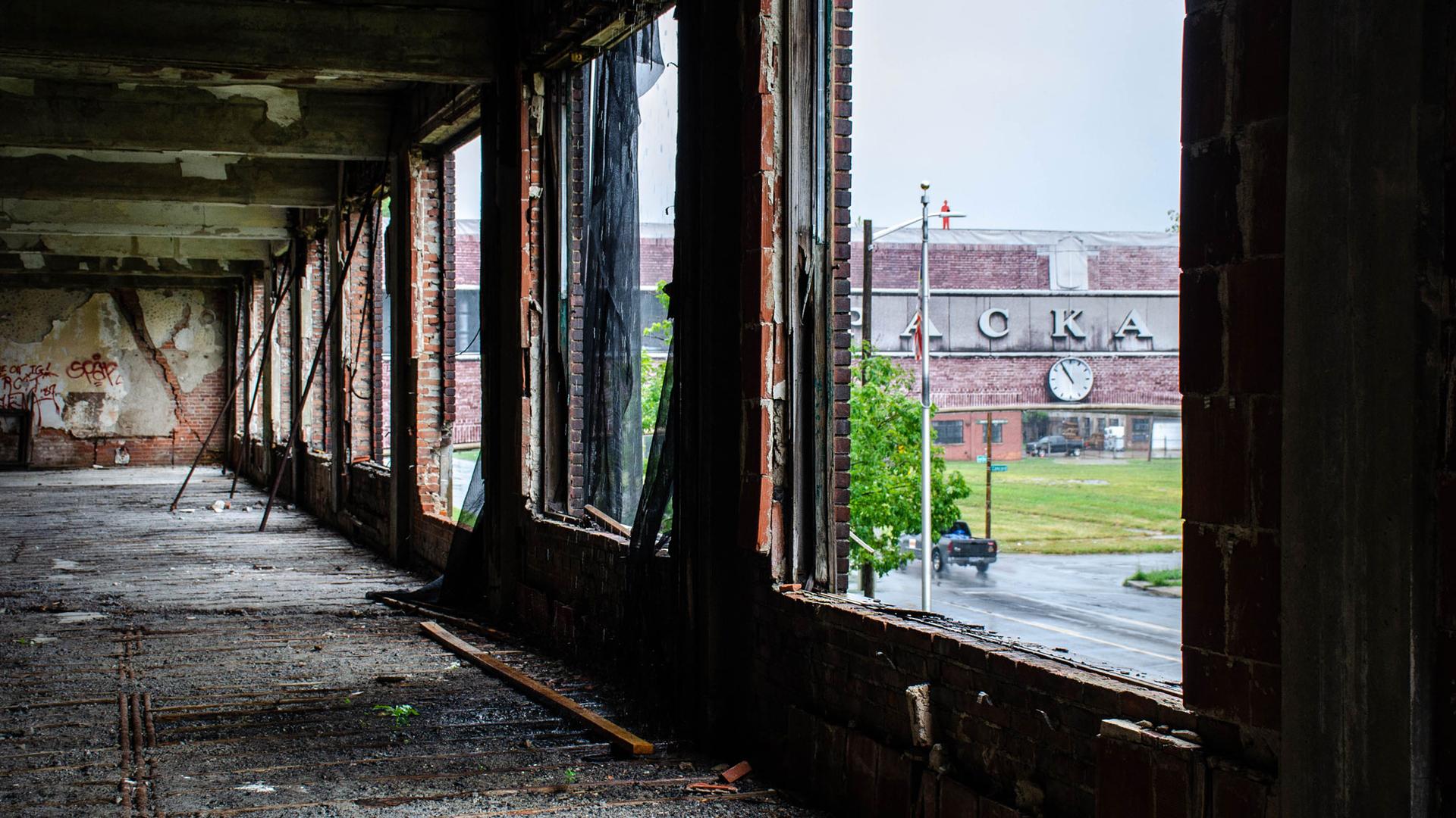 The lettering of the old Packard Plant in Detroit is seen on a brick bridge viewed through the ruins of a window in the factory.