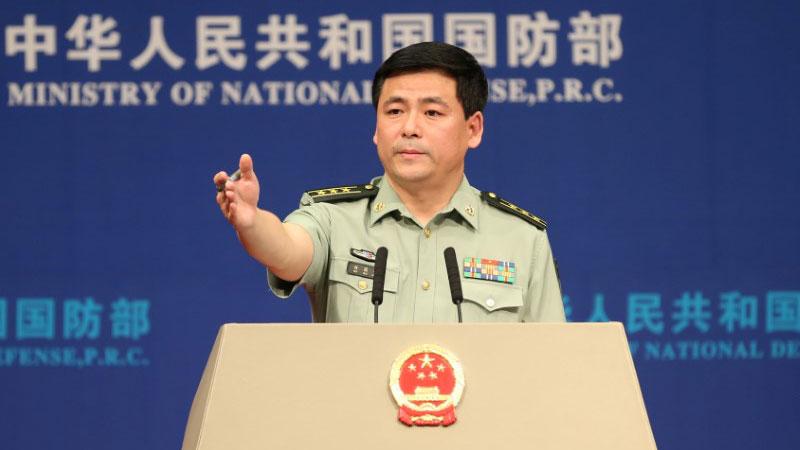 Chinese Defense Ministry spokesman Ren Guoqiang is shown at a podium with his arm outstretched.