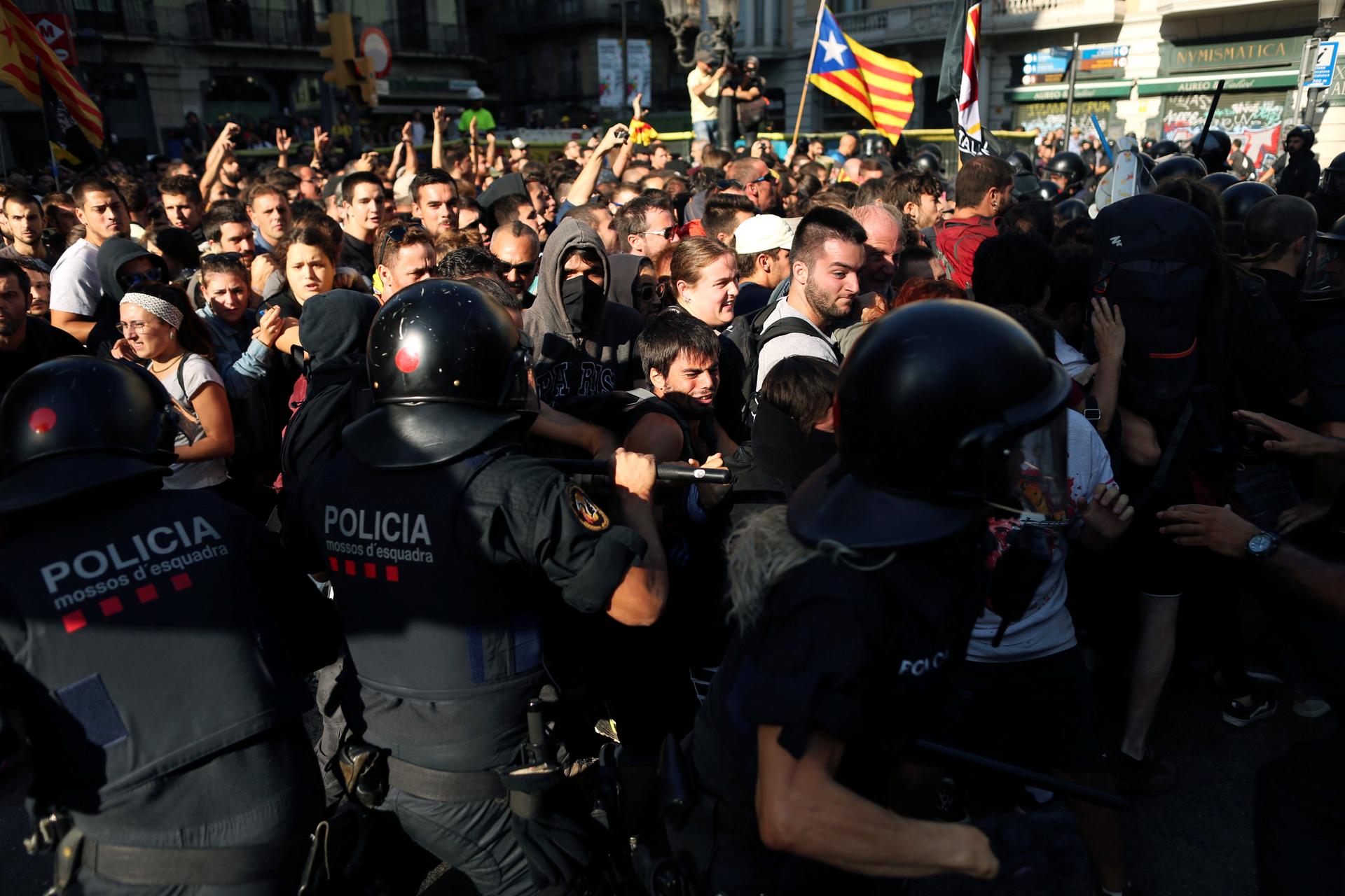 protesters clash with a Catalan flag waving in the background