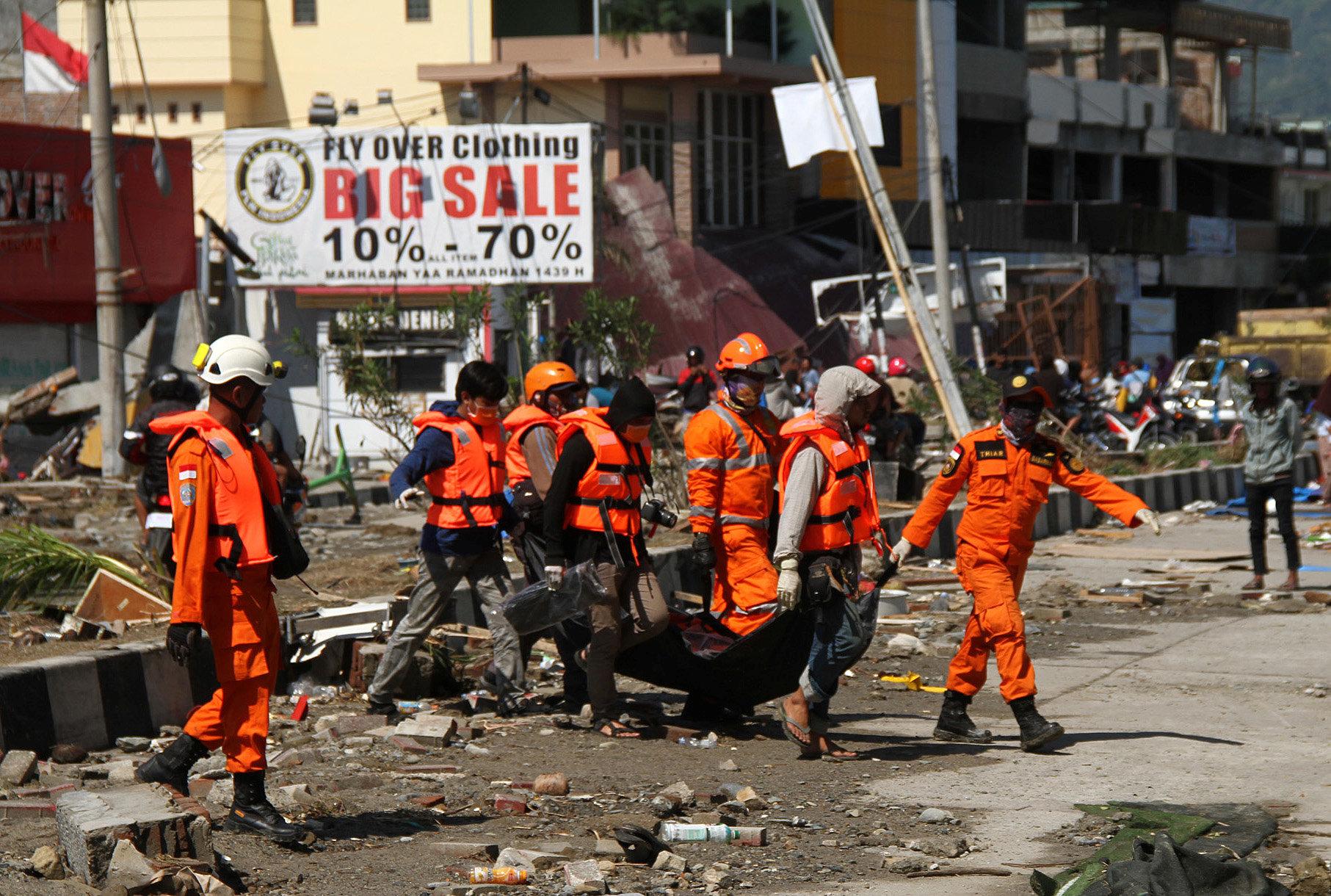 rescue workers dressed in orange carry a person on a gurney