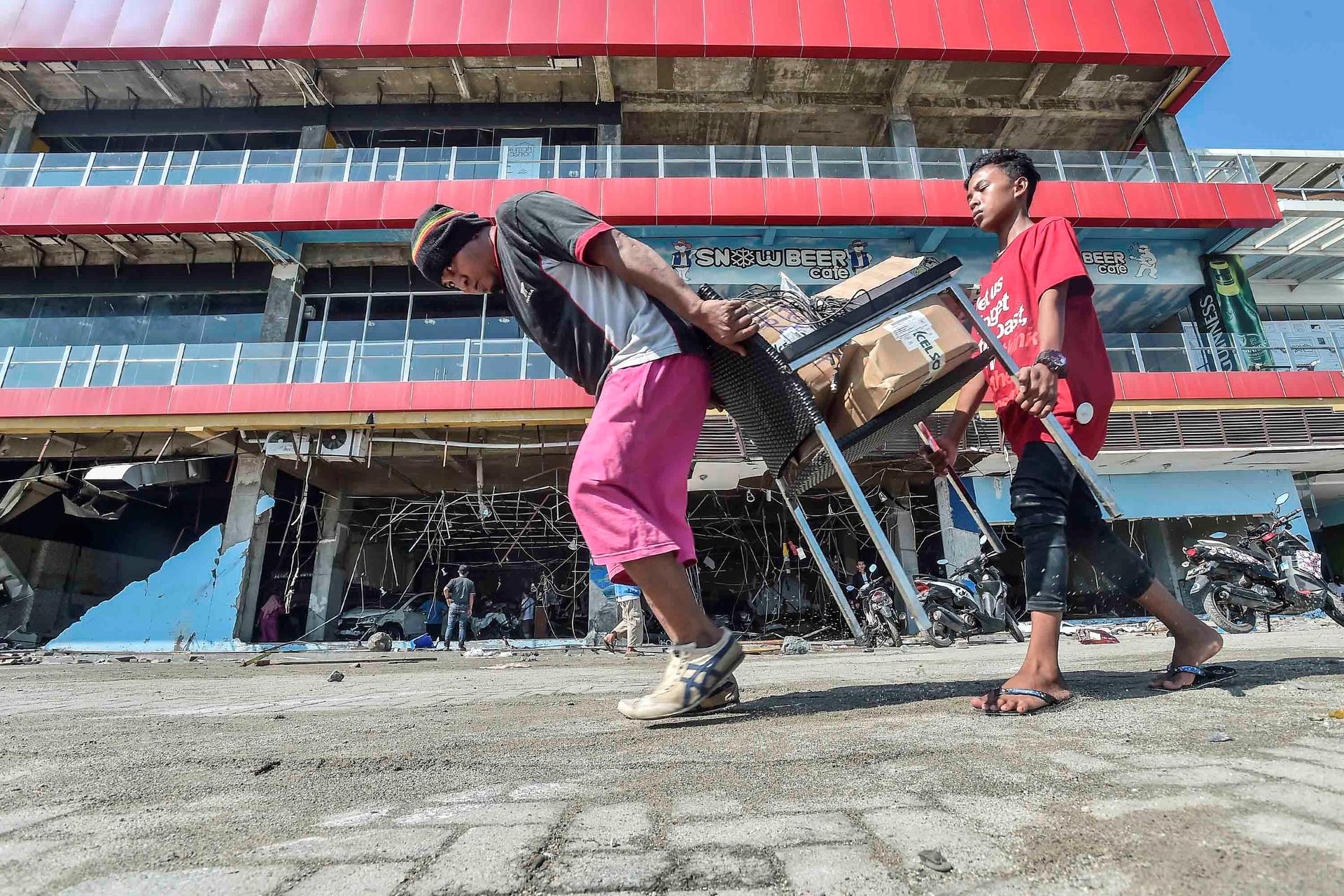 People carry away goods from a destroyed mall