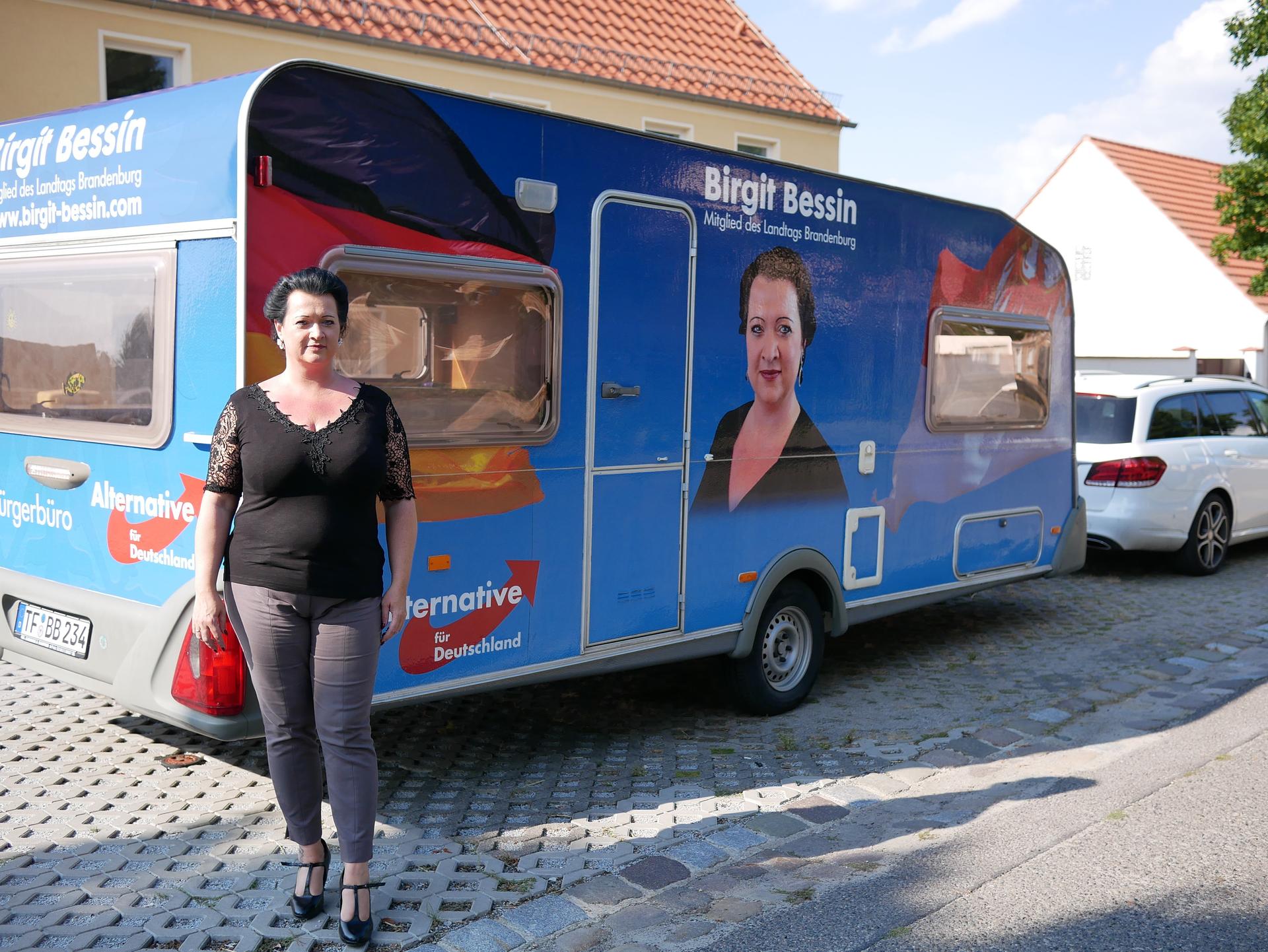 Birgit Bessin poses with a trailer bearing the logo of her party, the AfD