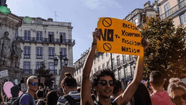 a man holds a protest sign in Lisbon 