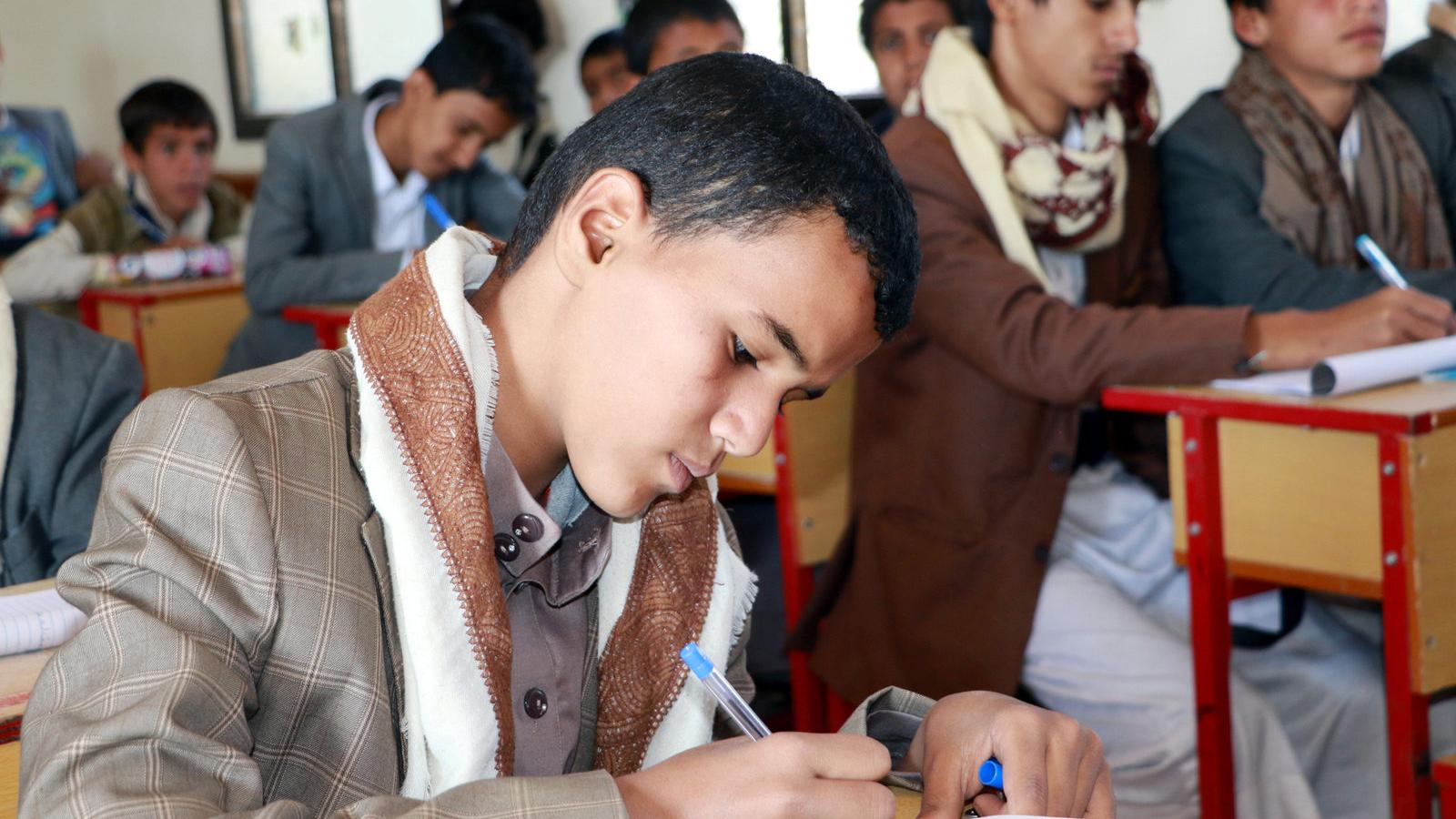 A boy sits at his desk in a classroom in Saada province, Yemen