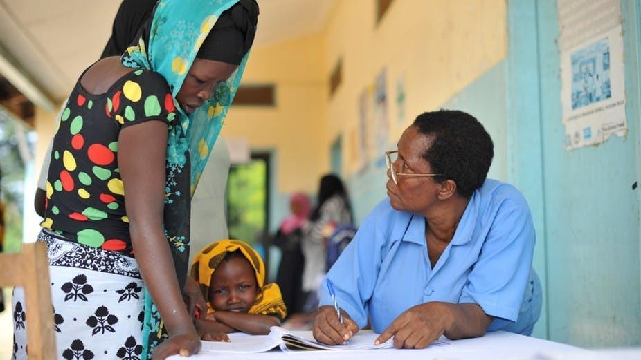 A young Tanzanian woman speaks to a male doctor. 