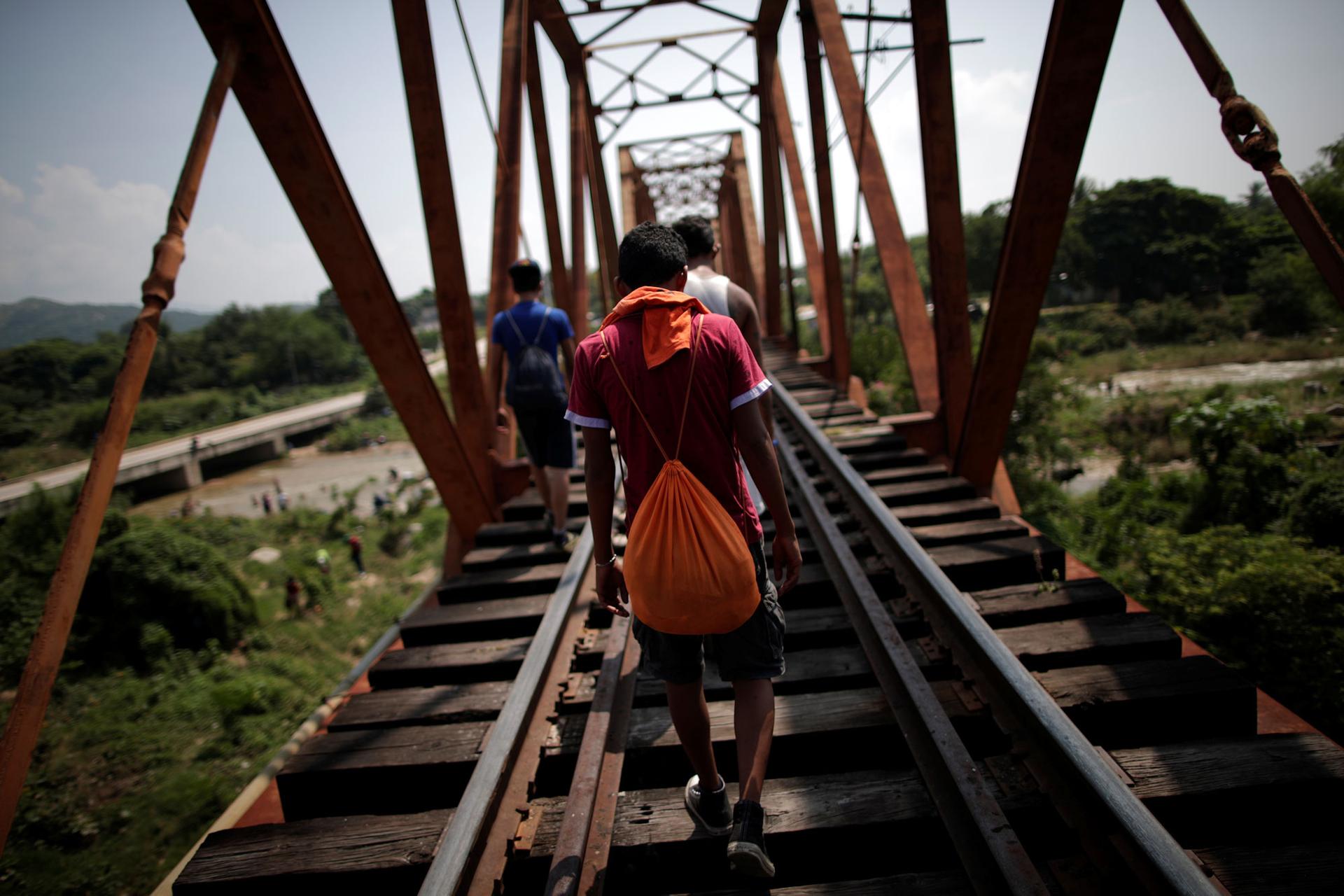 Migrants are shown walking along train tracks with their backs to the camera in Arriaga, Mexico Oct. 26, 2018.