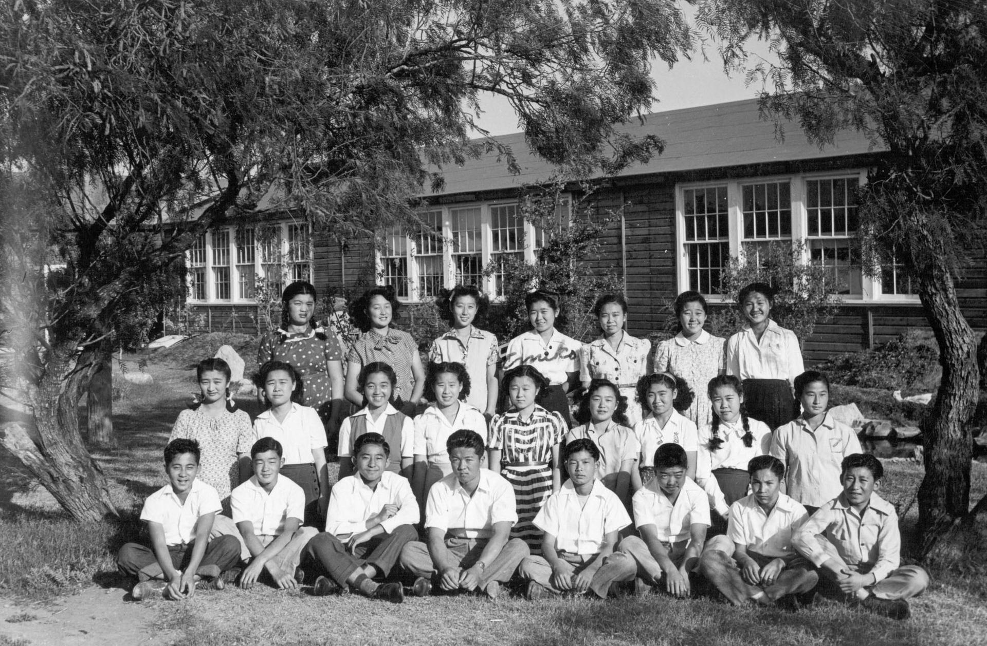 Three rows of students pose in front of a building
